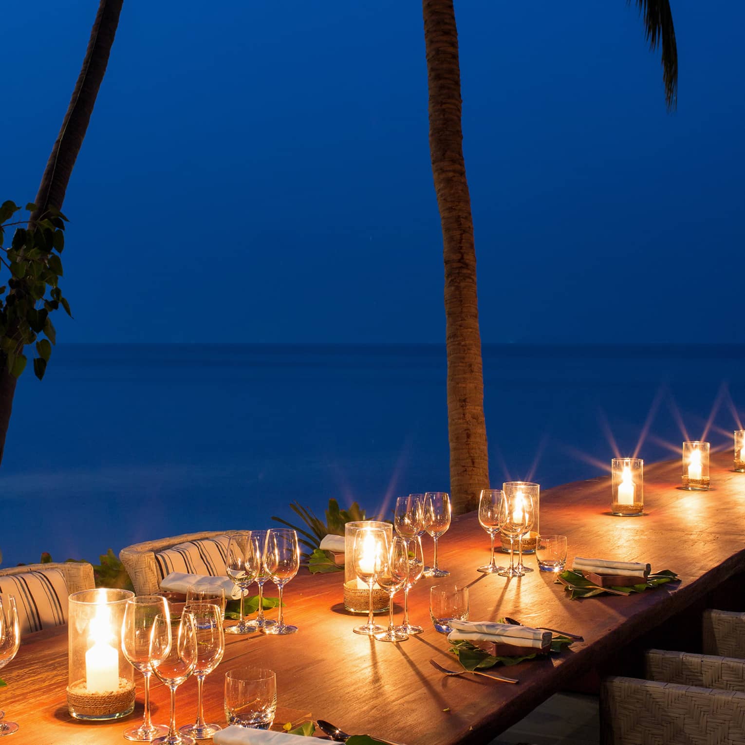 Table adorned with wine glasses and glowing candles with a view of the Gulf of Thailand,Table adorned with wine glasses and glowing candles with a view of the Gulf of Thailand