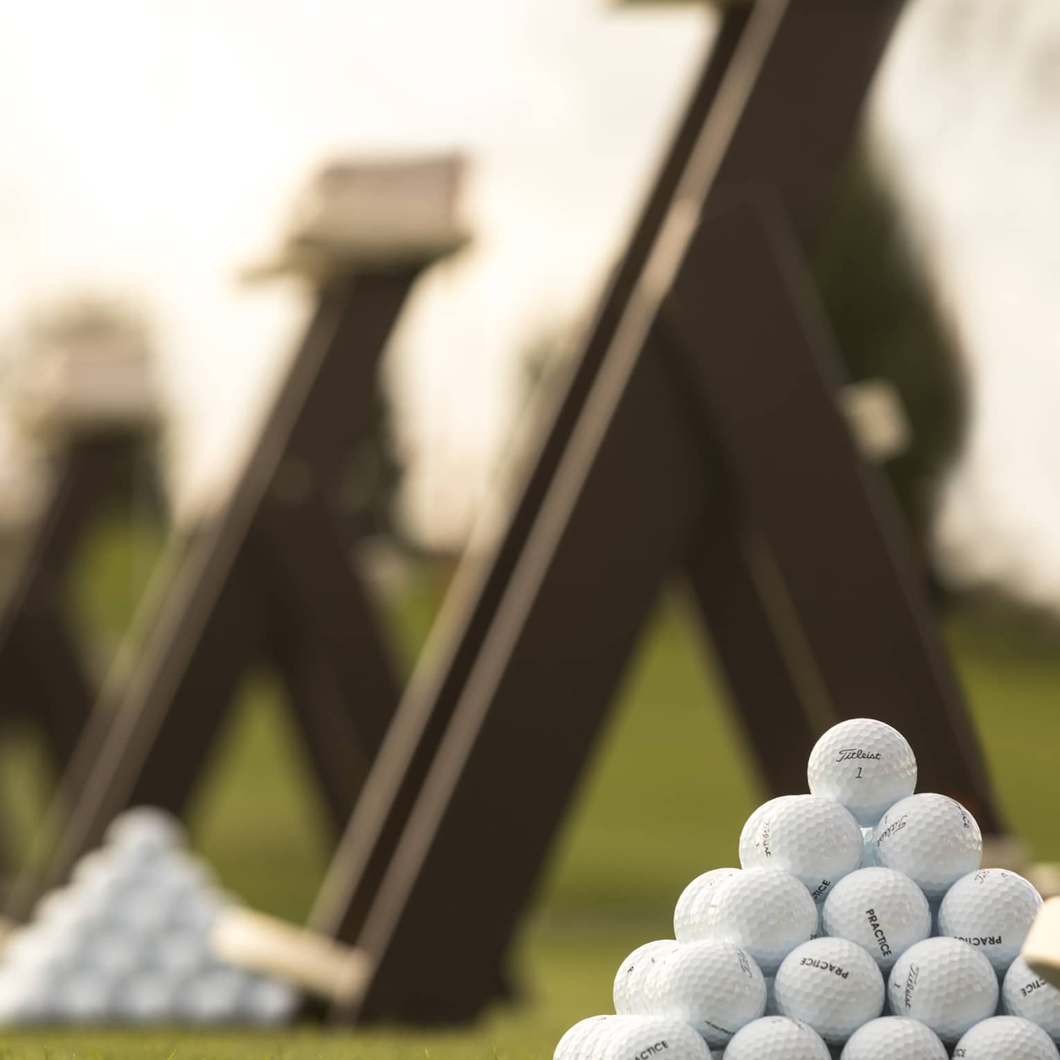 Stacks of white golf balls on lawn in front of wood panels