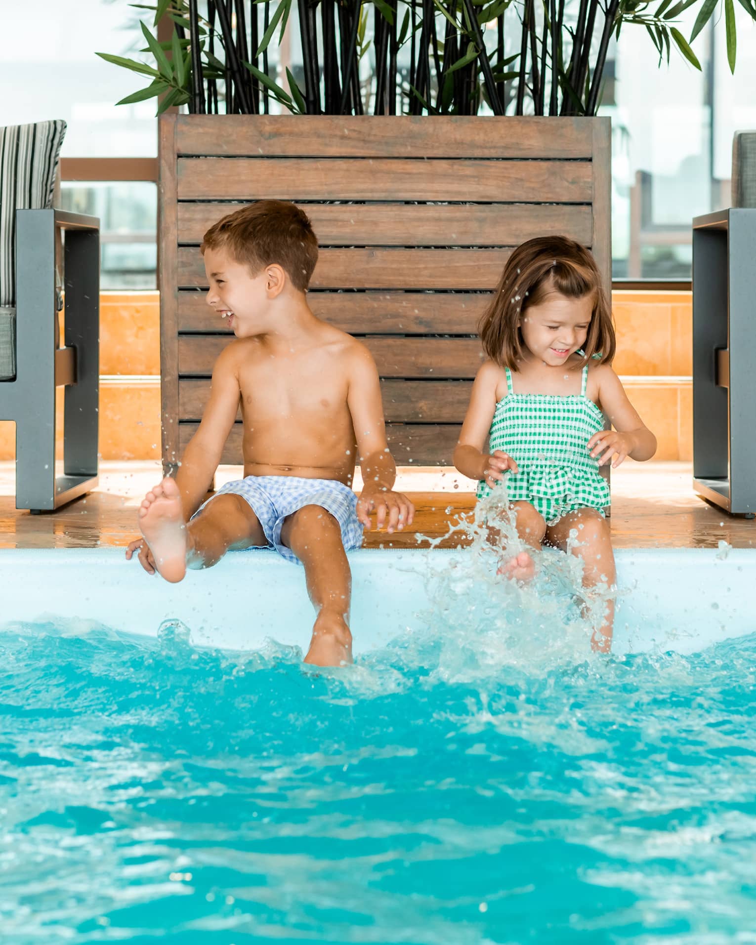 Two young children sitting on the edge of a pool.