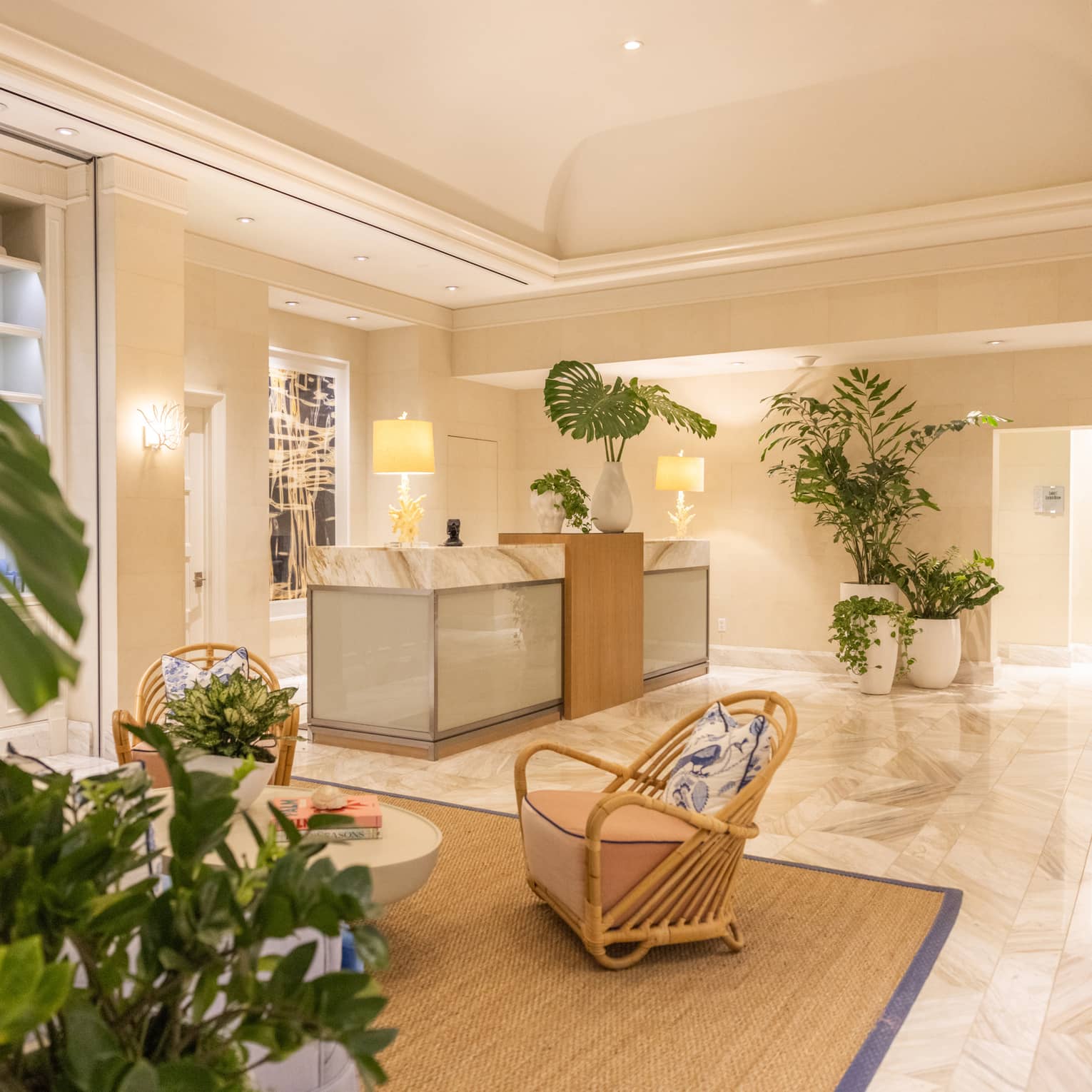 Spa lobby with white marble flooring, various trees in large white pots and a marble counter