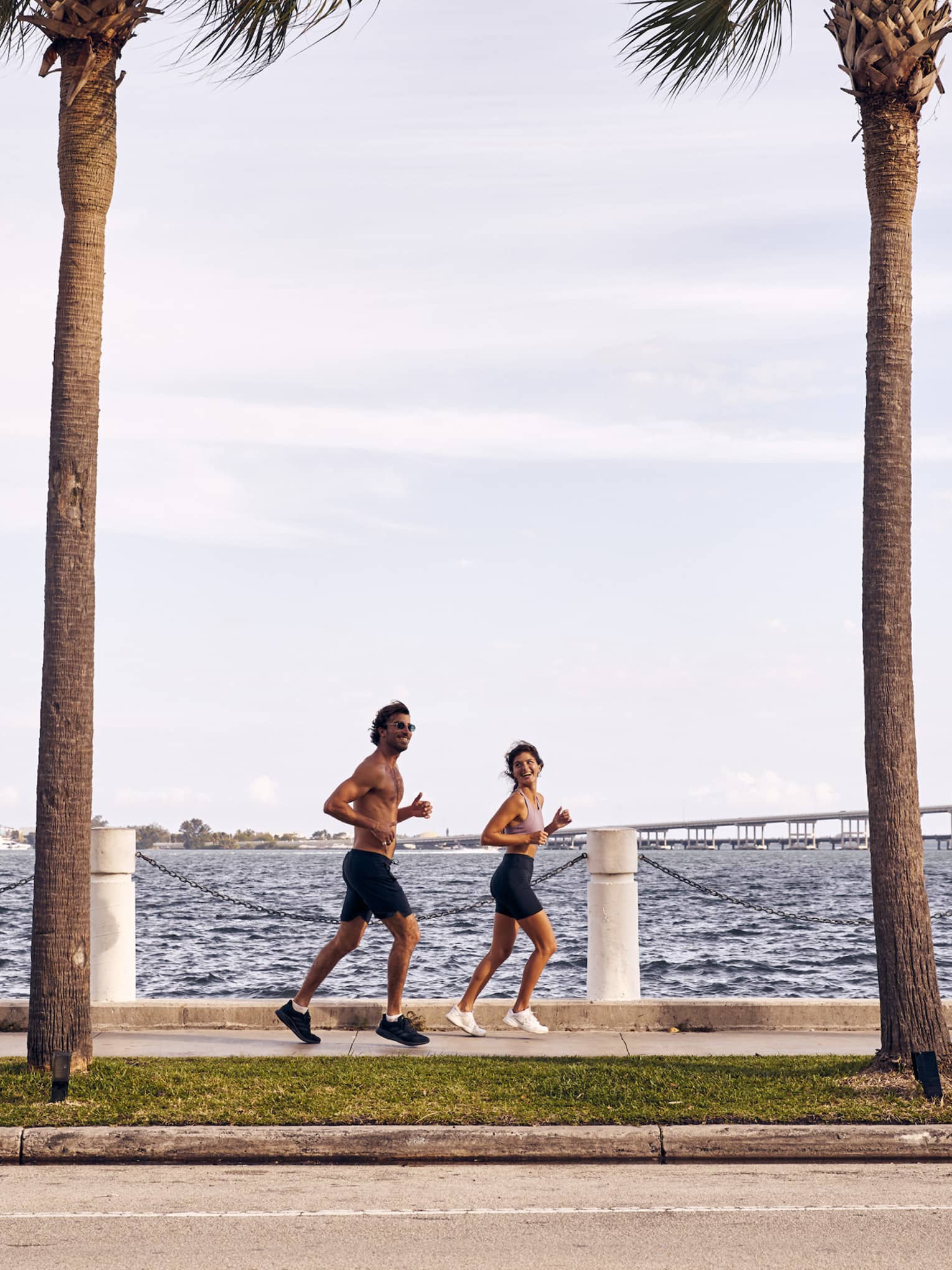 Man and woman running on sidewalk next to water