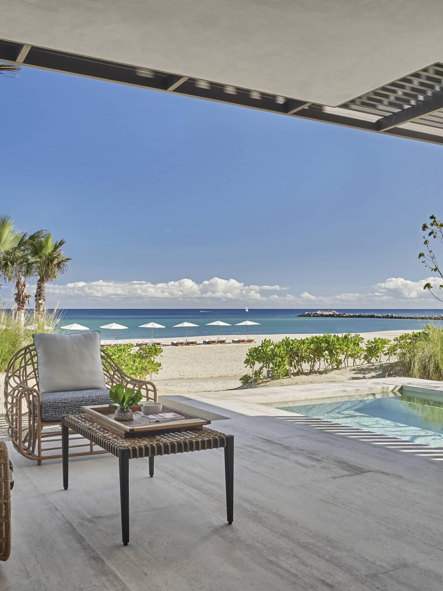 Outdoor terrace with beach and ocean view, small pool, two arm chairs and table