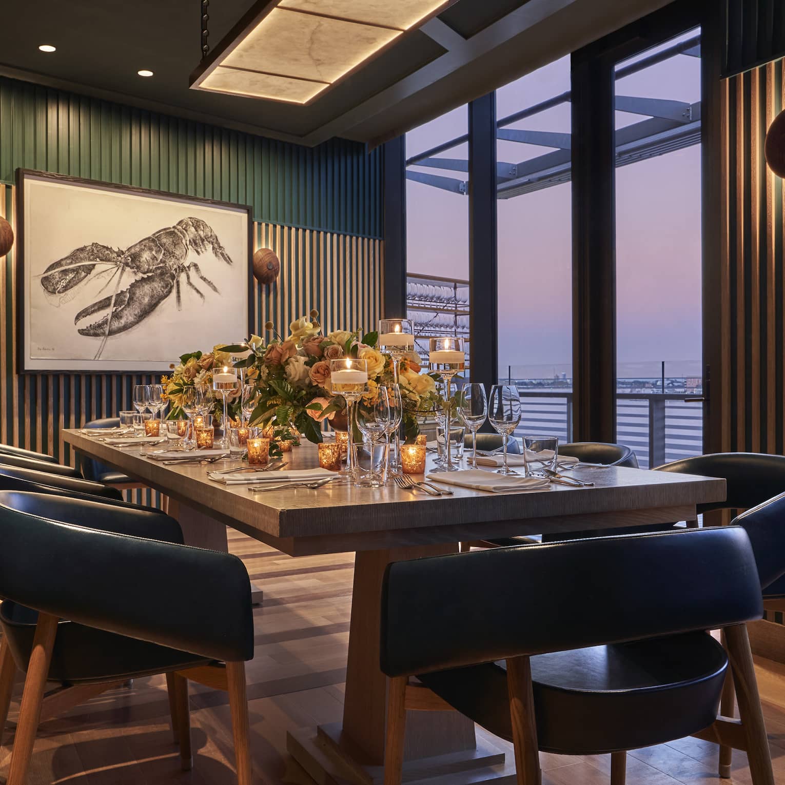 A private dining room with a large table, black chairs and large windows.