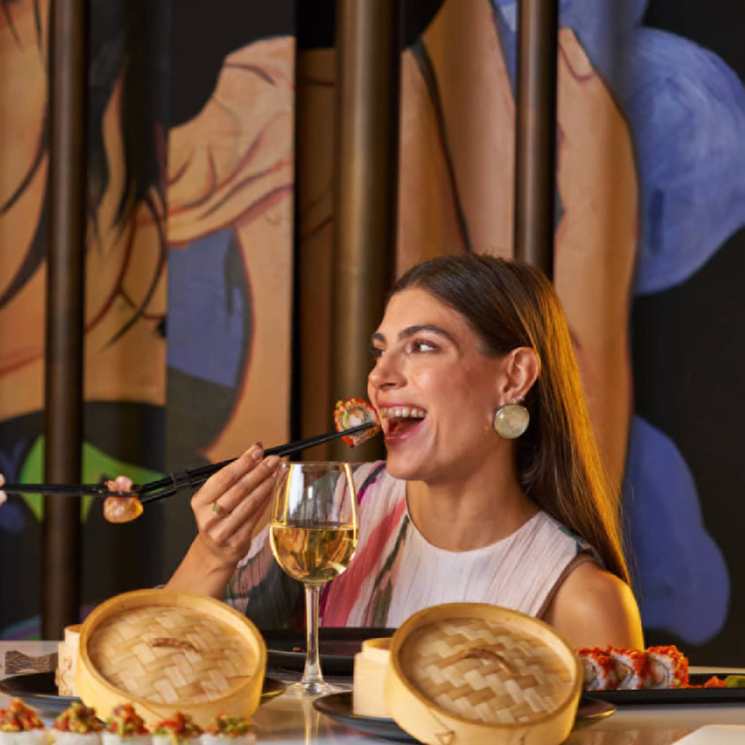 Two people enjoy dim sum with chopsticks from small bamboo steamer baskets are restaurant