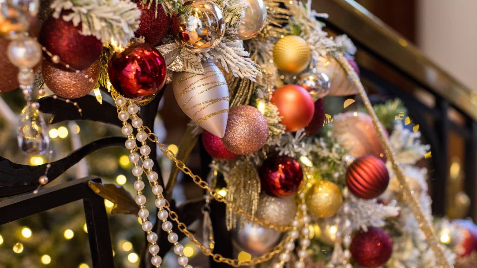 Red and gold ornaments placed on garland on a staircase