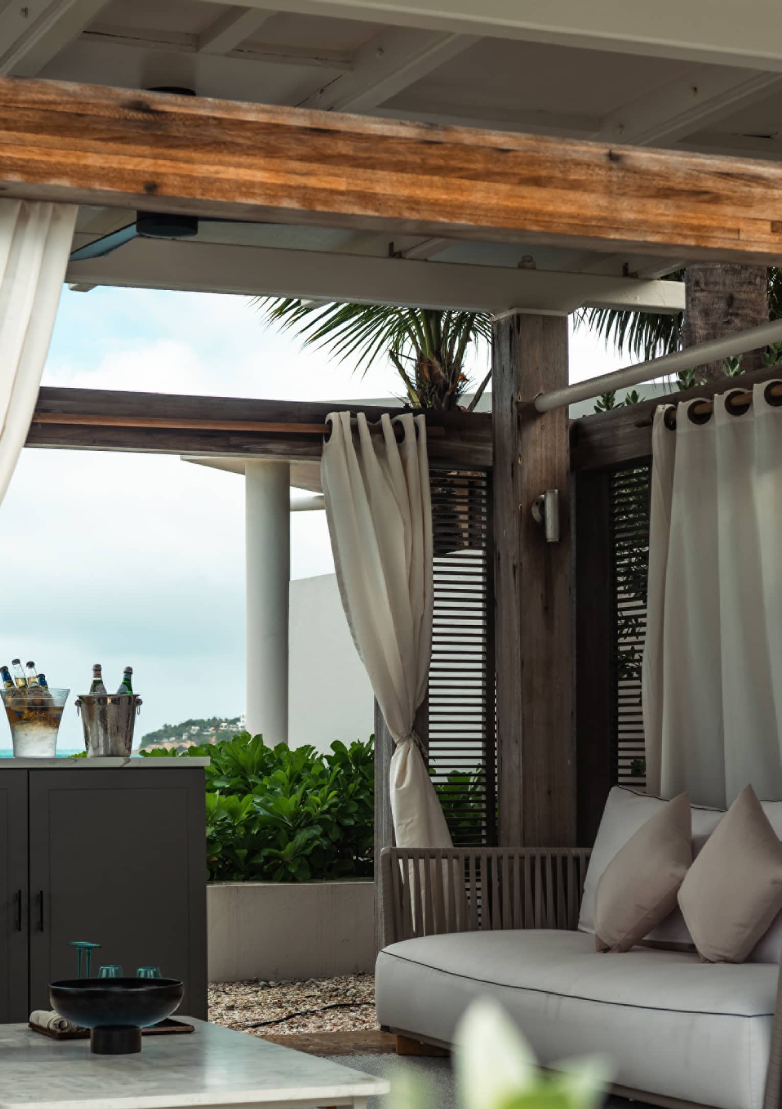 A cabana with a marble table and couch surrounded by palm trees