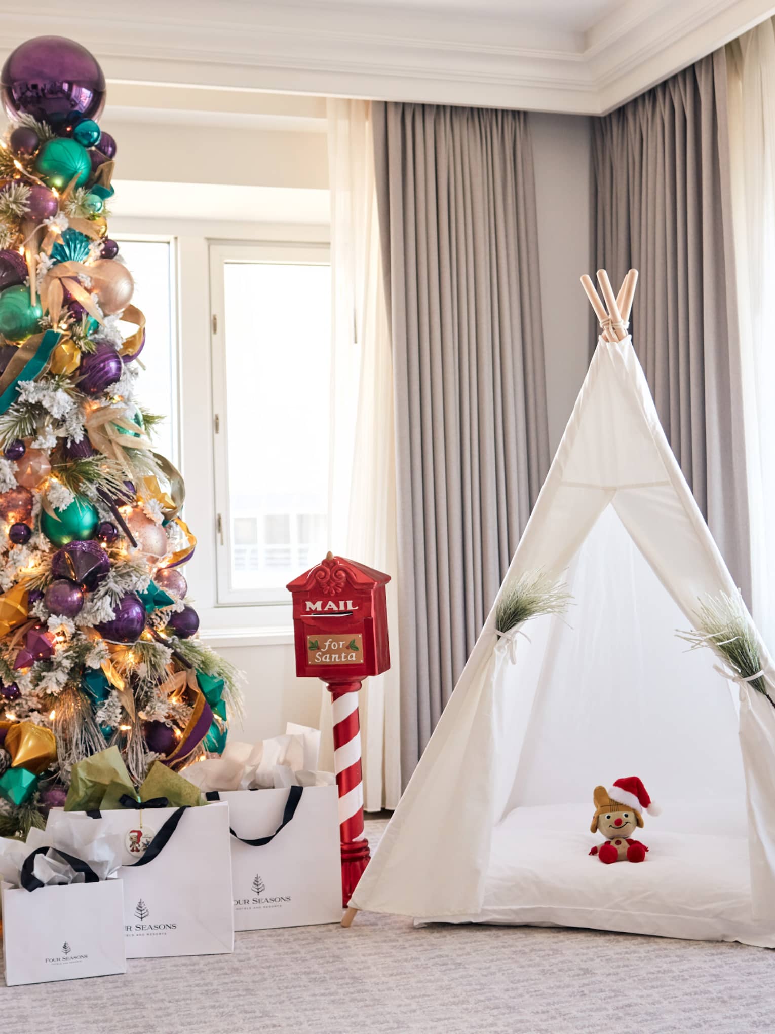 A small tent next to a Christmas tree with gifts underneath.