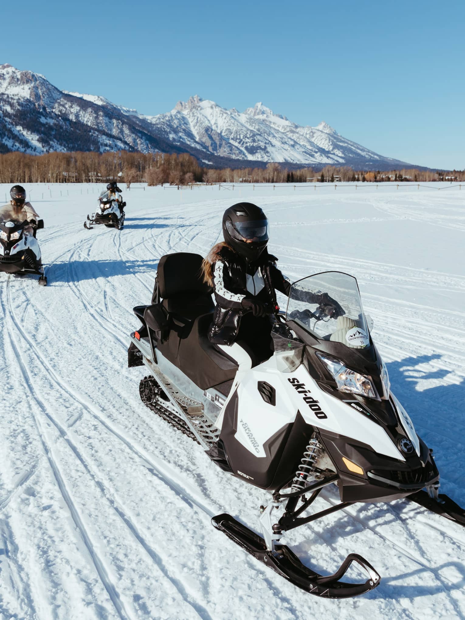Three people on snowbmobiles.