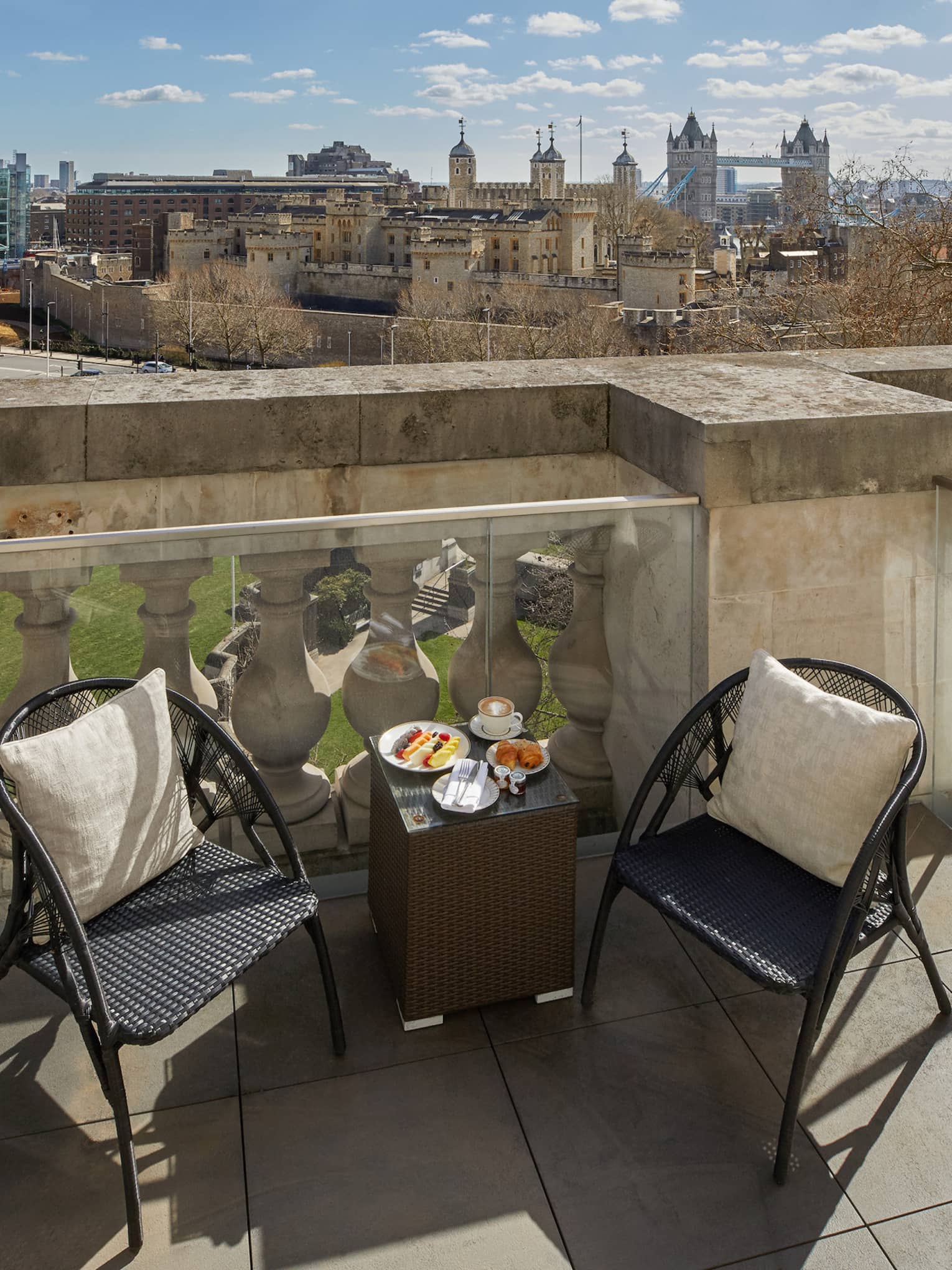 An outdoor terrace of tone with a small table and two small chairs.