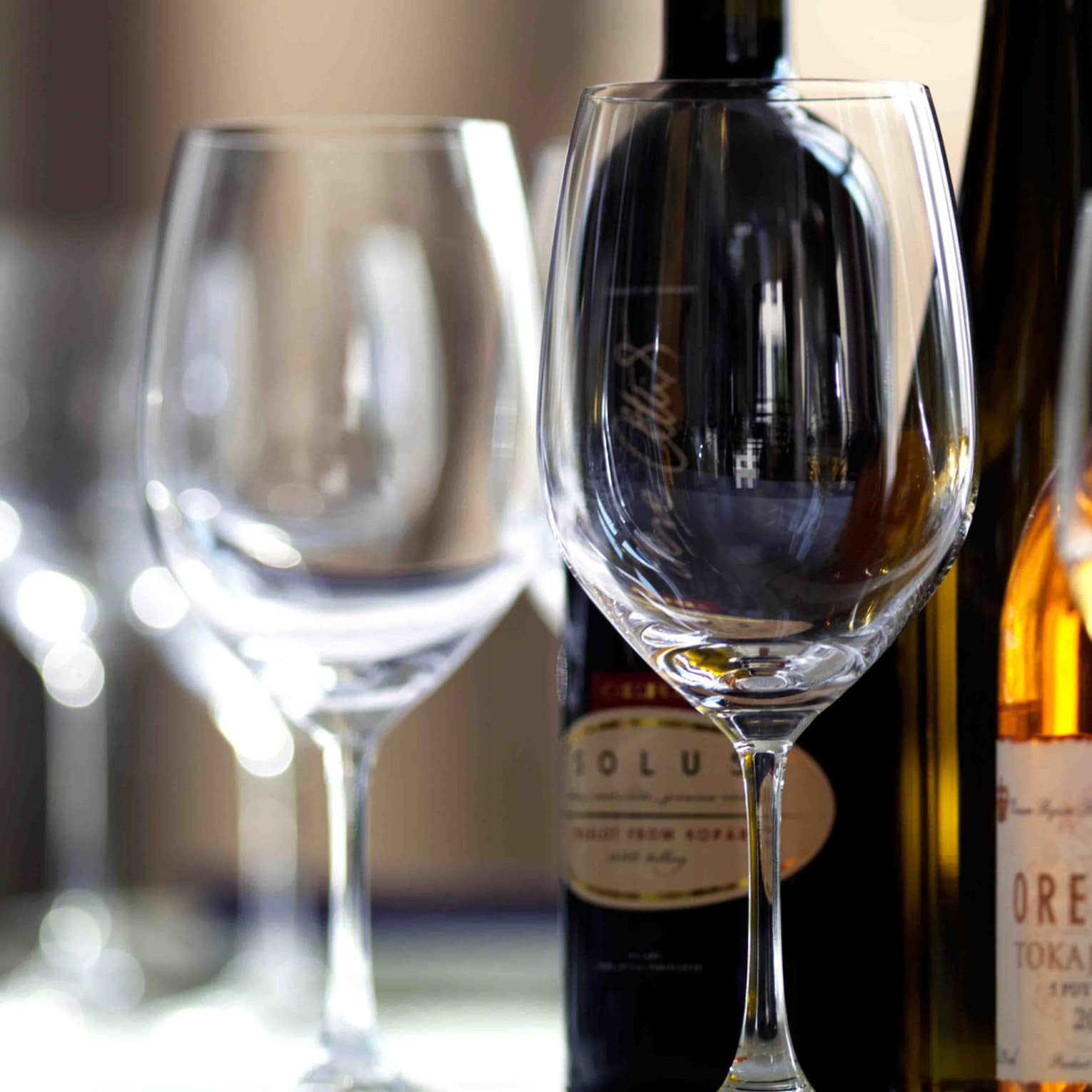 Close-up of wine glasses in front of bottles