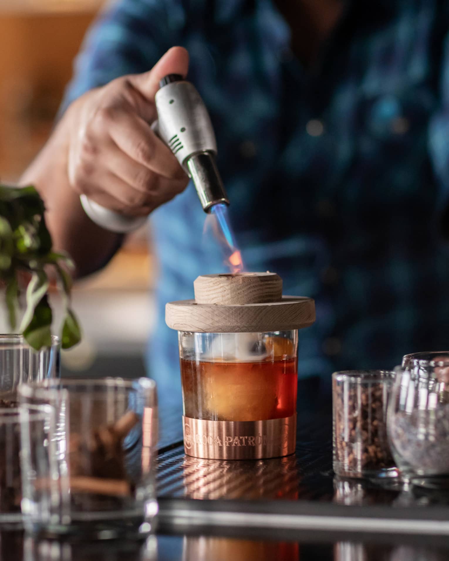 Bartender standing at the bar and using a whiskey torch to make a drink