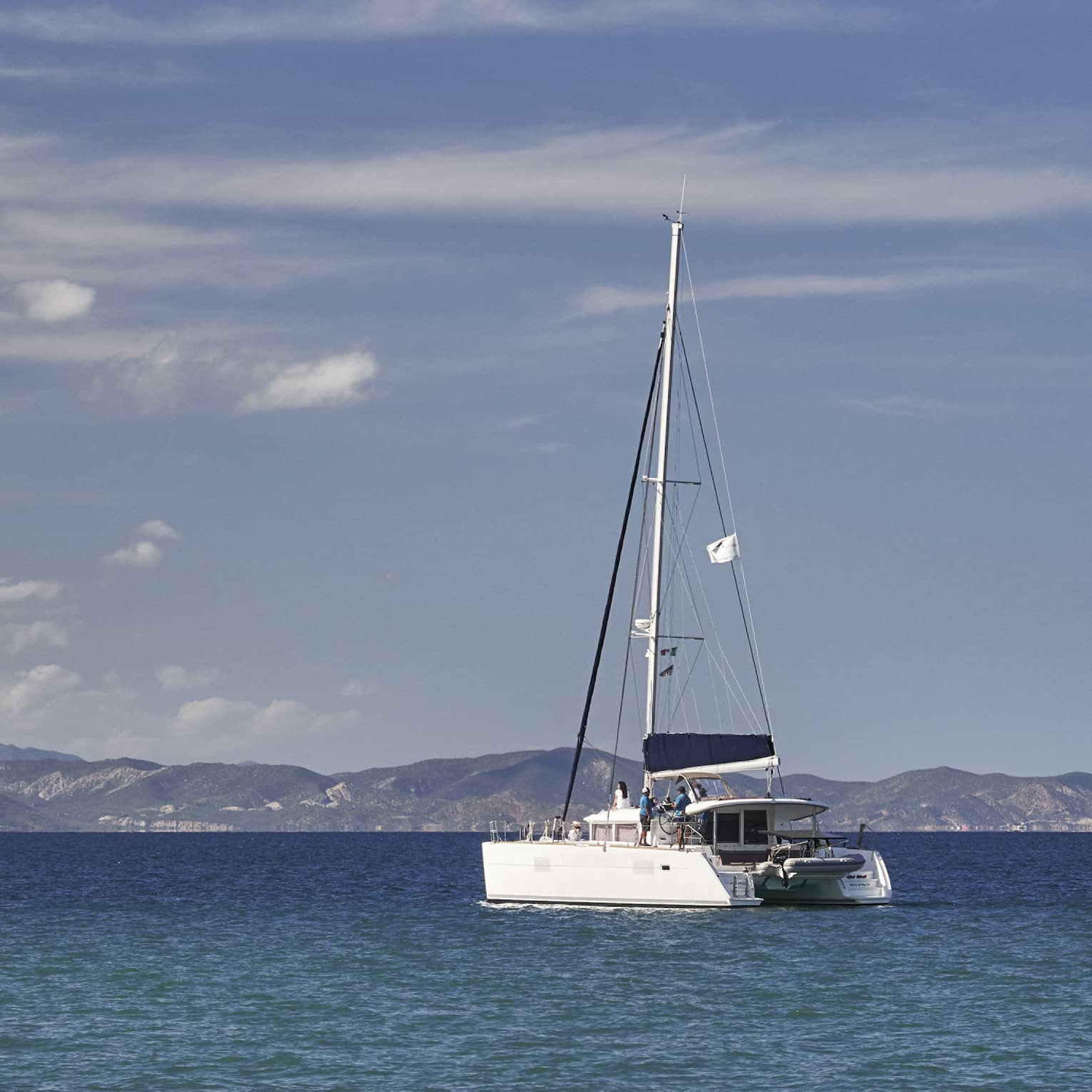 A boat sailing on the ocean with mountains in the distance.
