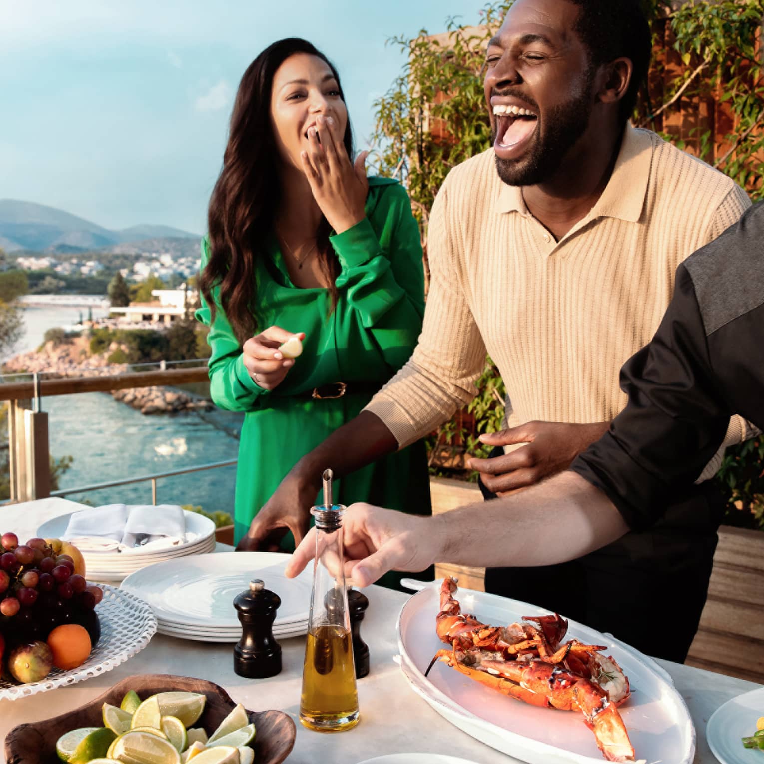 Couple enjoying food prepared by chef outside with view of water.