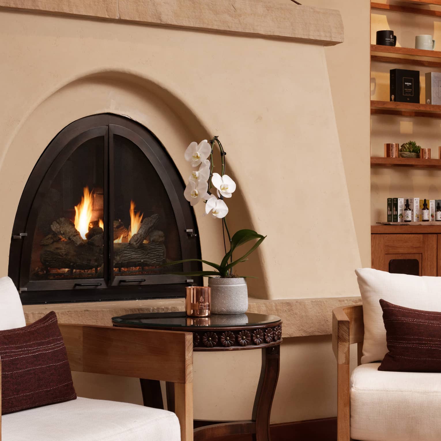 A sitting area with a fireplace, chairs and a small table.