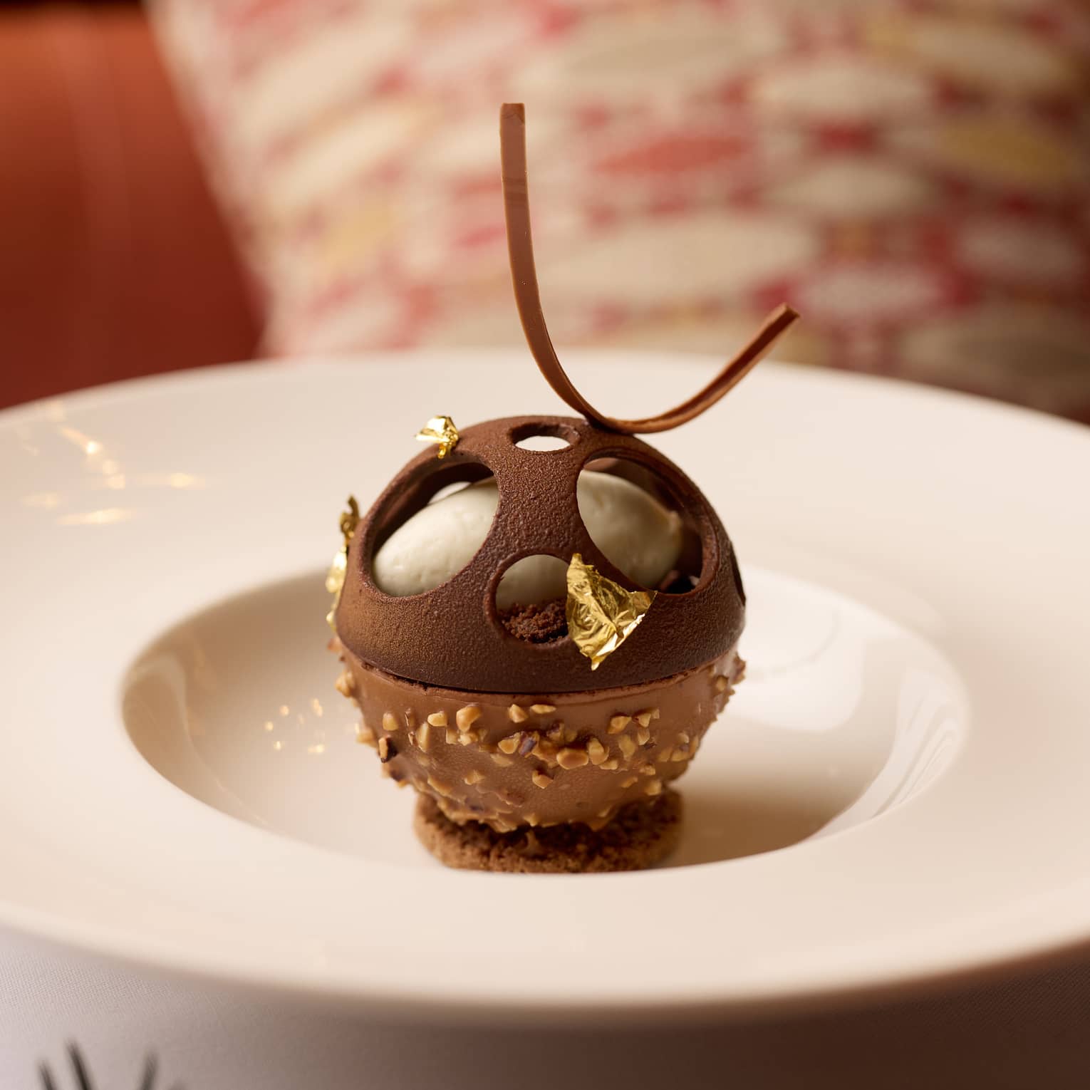 An artistic sphere-shaped dessert in a shallow bowl