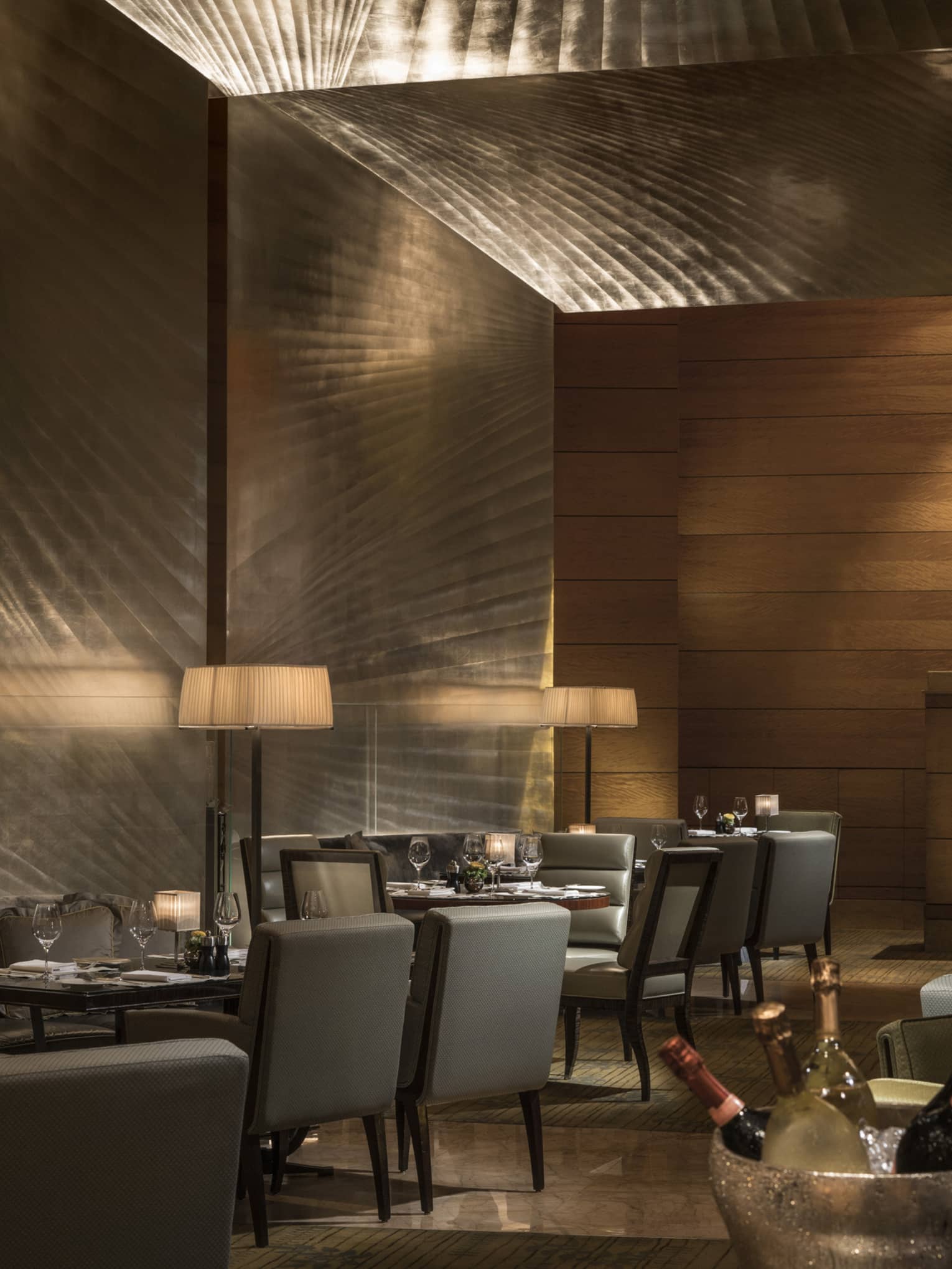 Elegant restaurant dining area with softly lit tables, upholstered chairs, and ambient lighting, set for a formal dinner service.