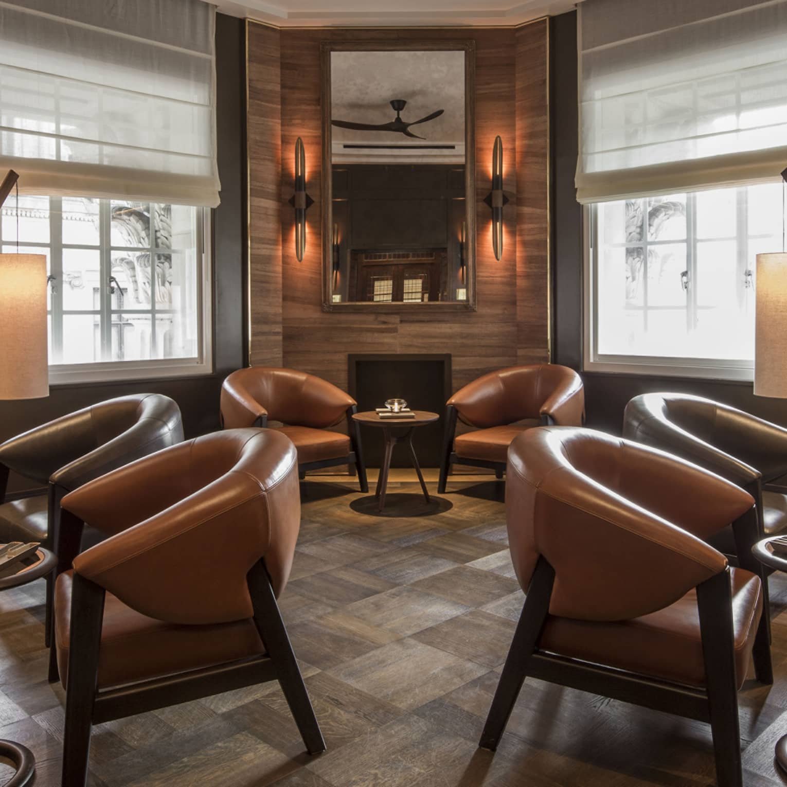 A warmly lit, sophisticated lounge with leather chairs and banquettes arranged in groups around small cocktail tables.