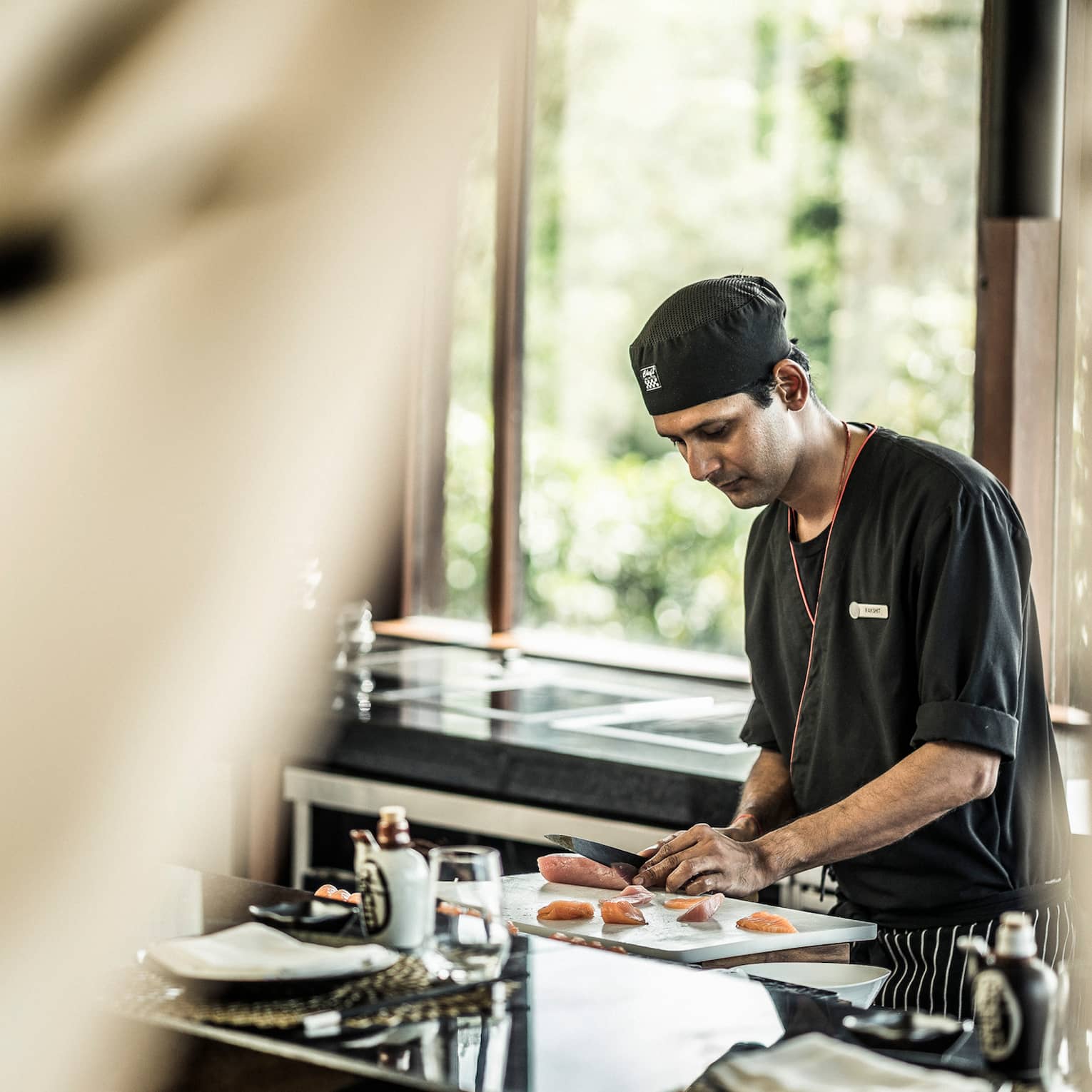 KOI chef prepares sushi at counter in brightly lit room