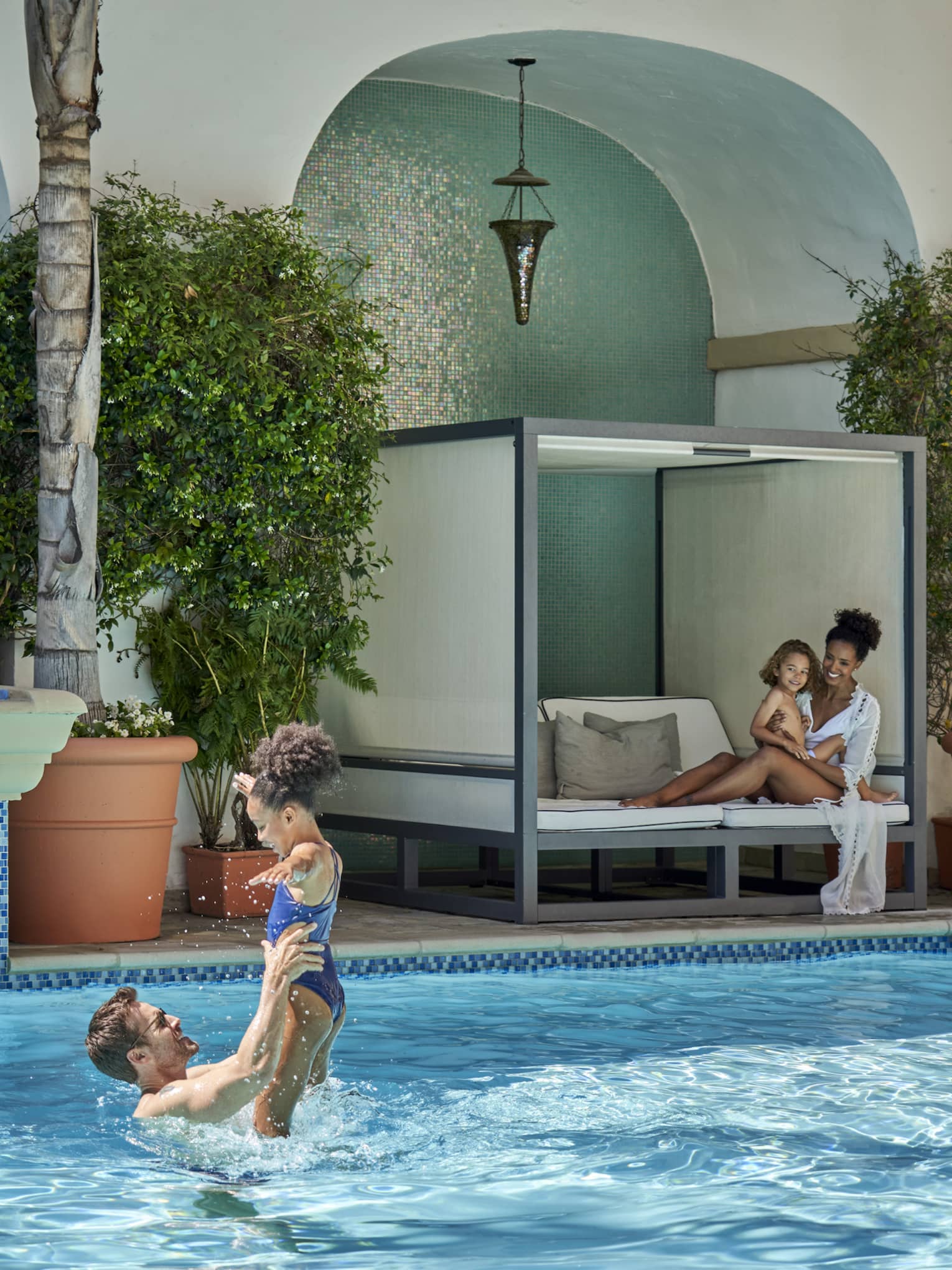 A family playing and sitting by an outdoor pool.