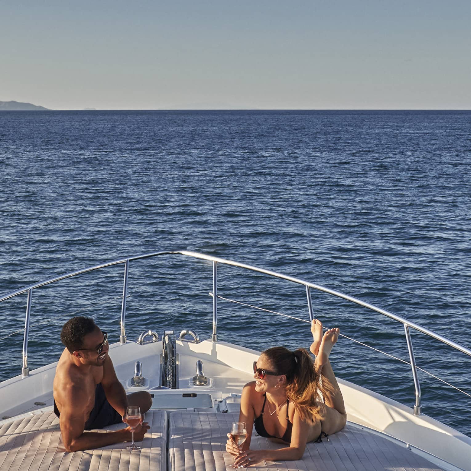 Man and woman lay on front of yacht