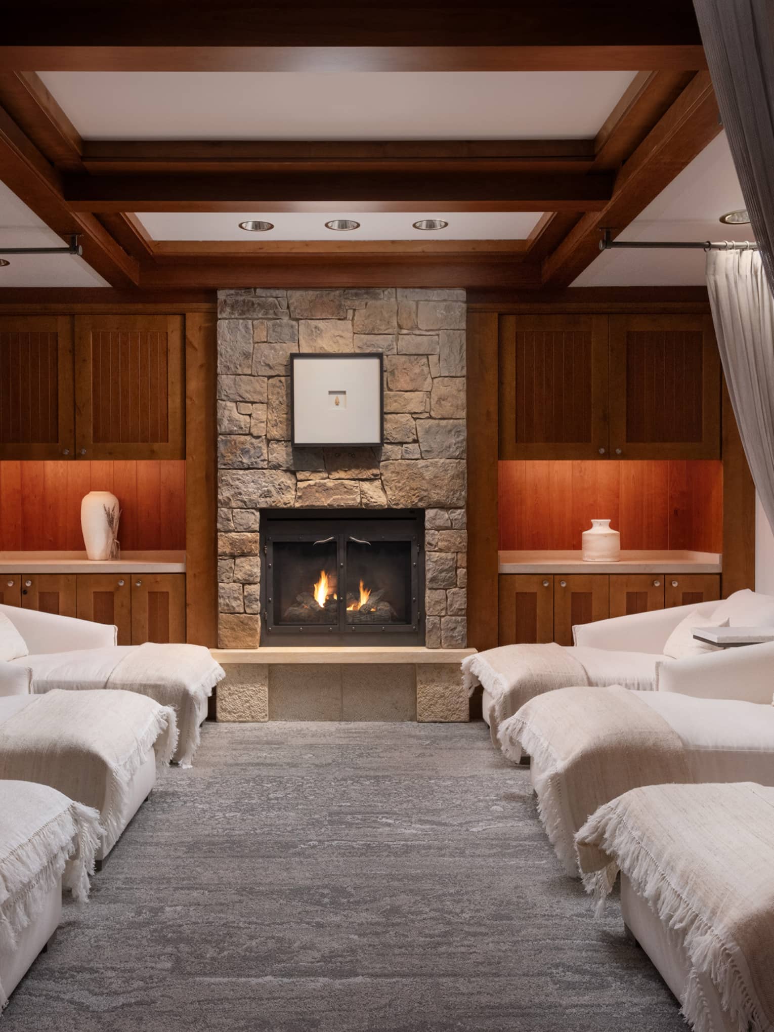 Lounge with spa beds, a fireplace and grey curtains.