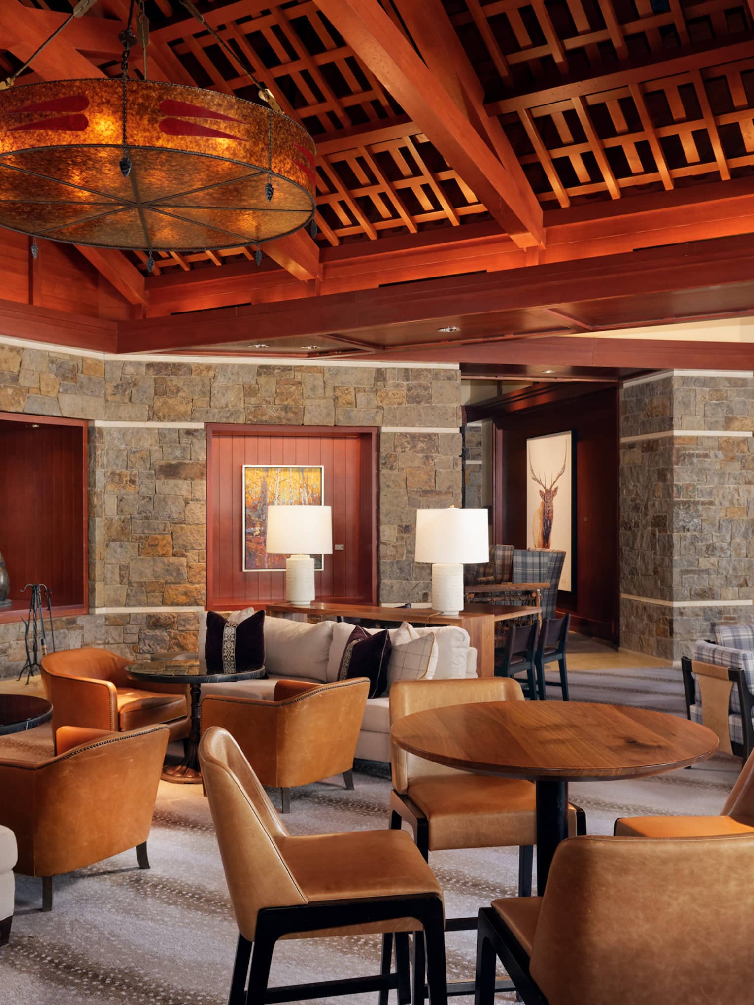 Luxury resort lounge and restaurant, with wooden beamed ceilings, stone walls, fireplace and leather chairs
