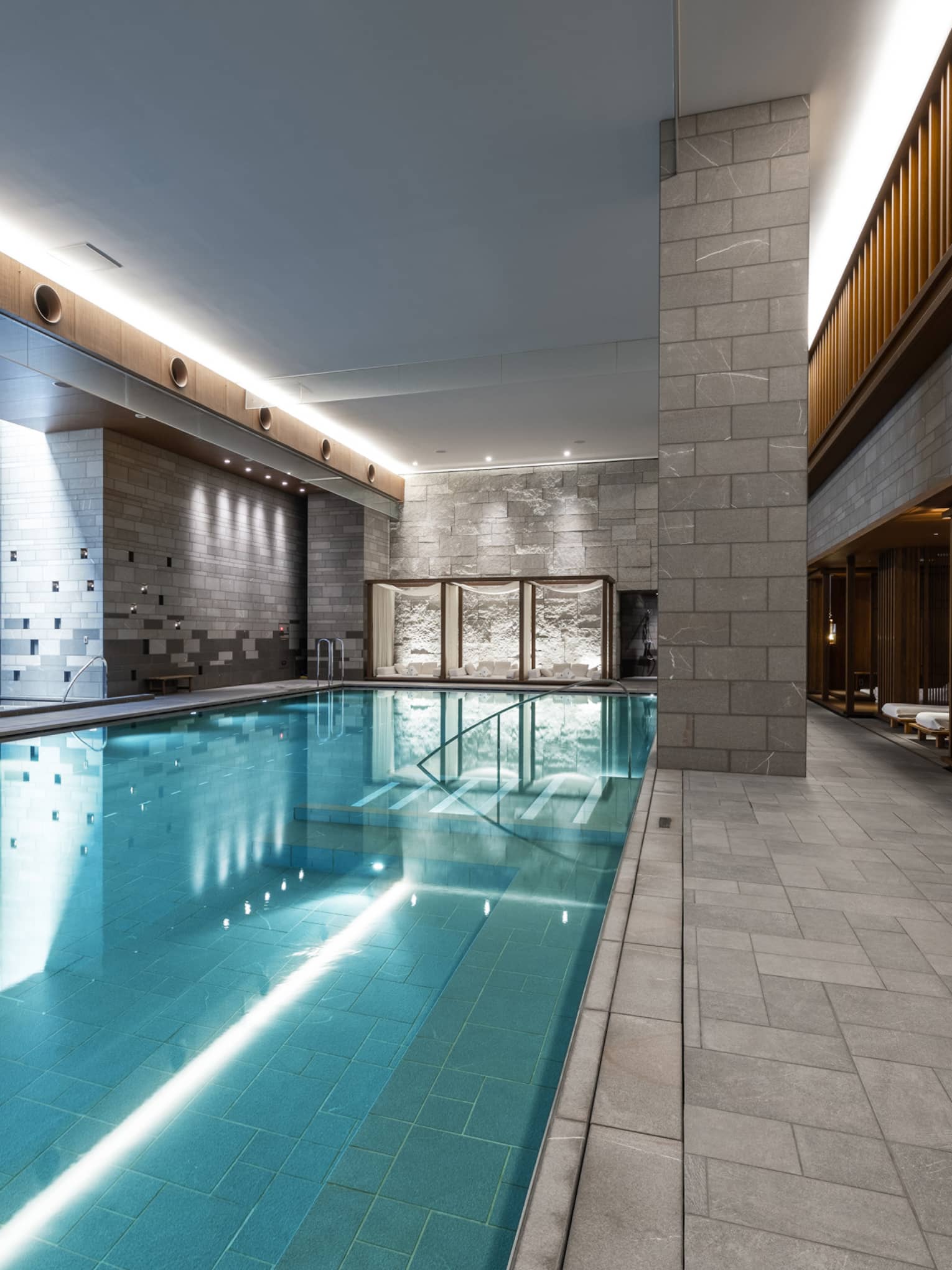 Indoor spa pool with chaise longues and grey columns