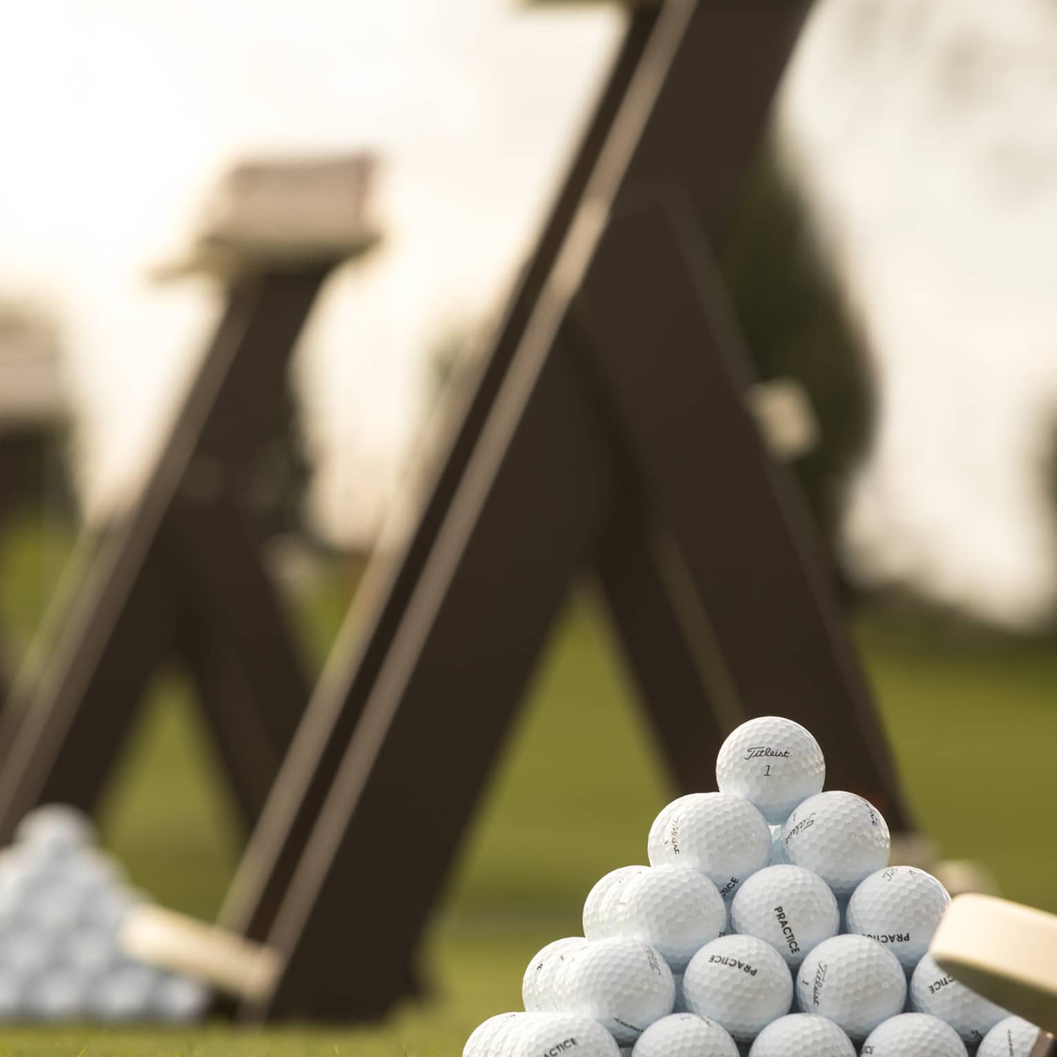 Stacks of white golf balls on lawn in front of wood panels