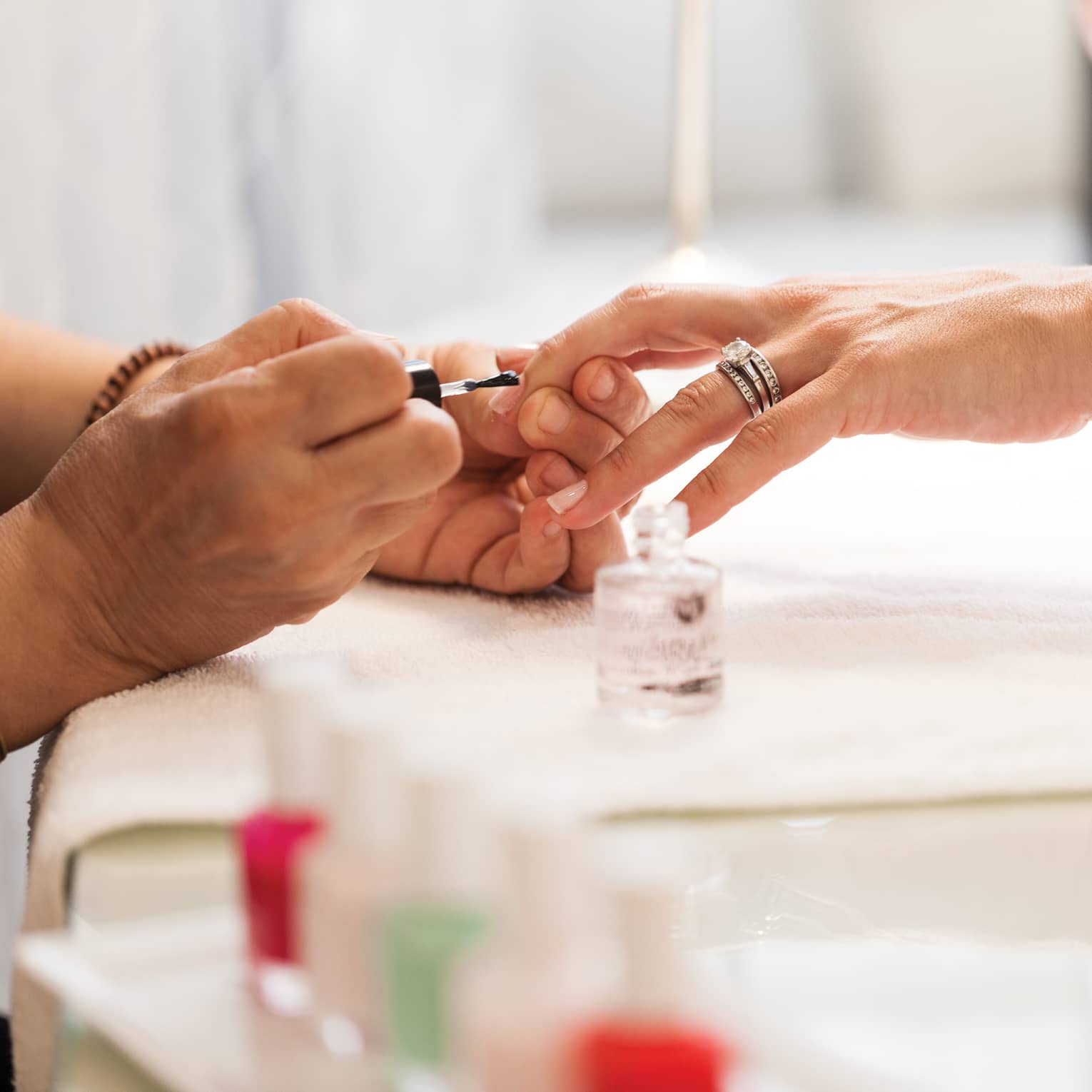 Close-up of woman in white robe getting clear polish manicure at spa table