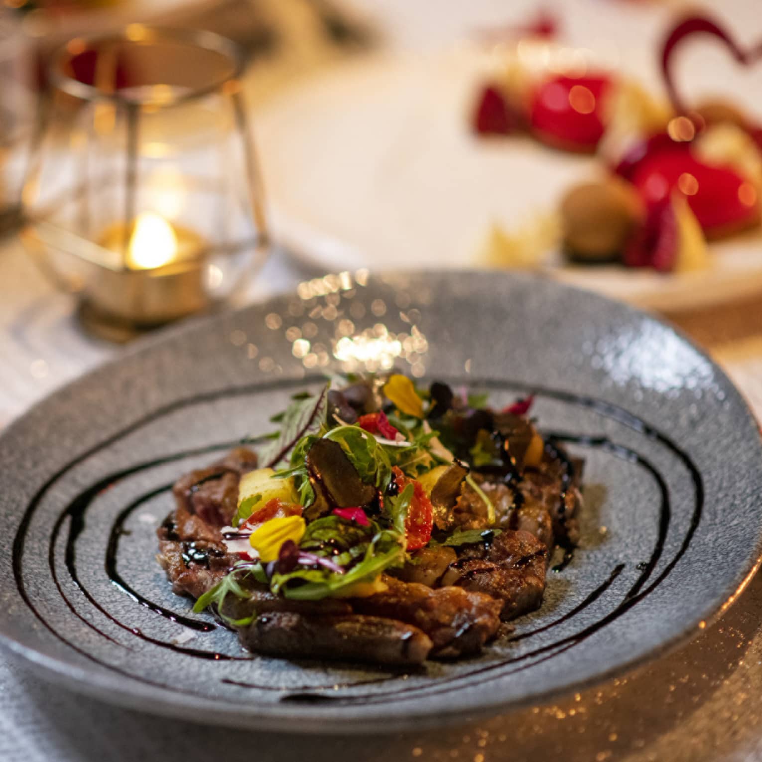 Roses and candles around dinner plate on table
