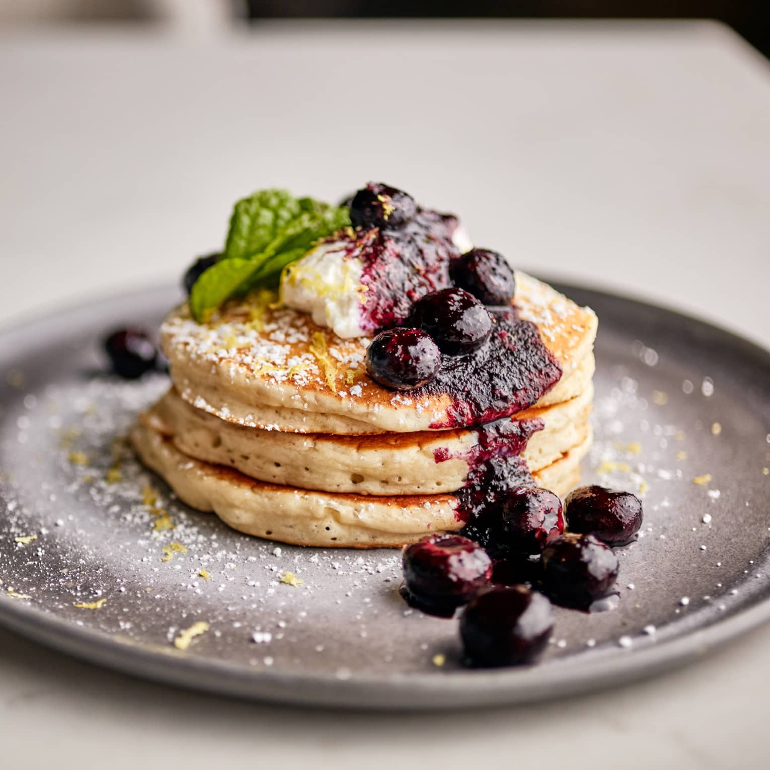 Three pancakes with blueberries on top.