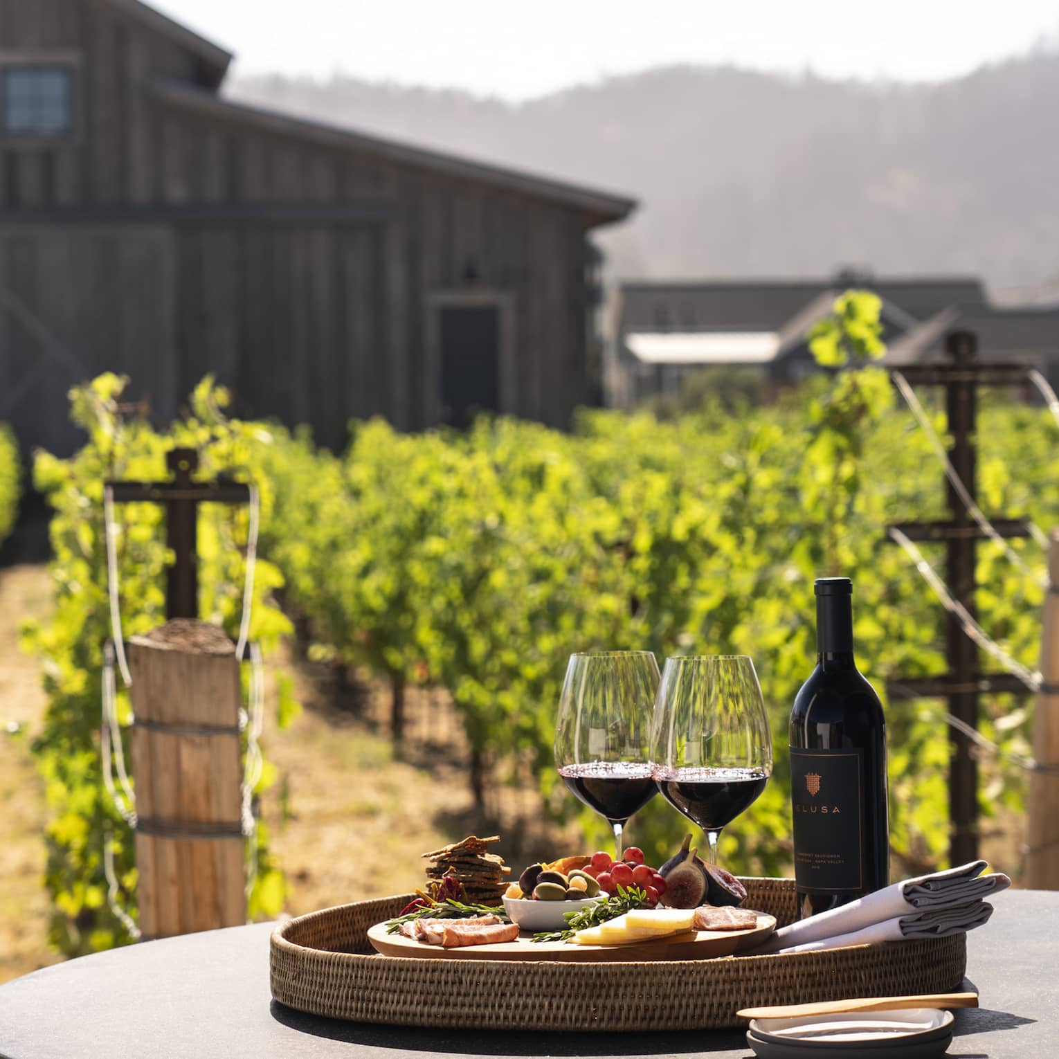 Two wine glasses with a plate of snacks on an outdoor dining table.