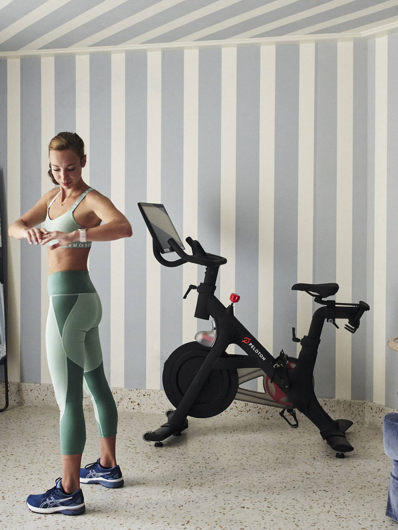 A woman in workout clothes in a hotel room with a stationary bike.