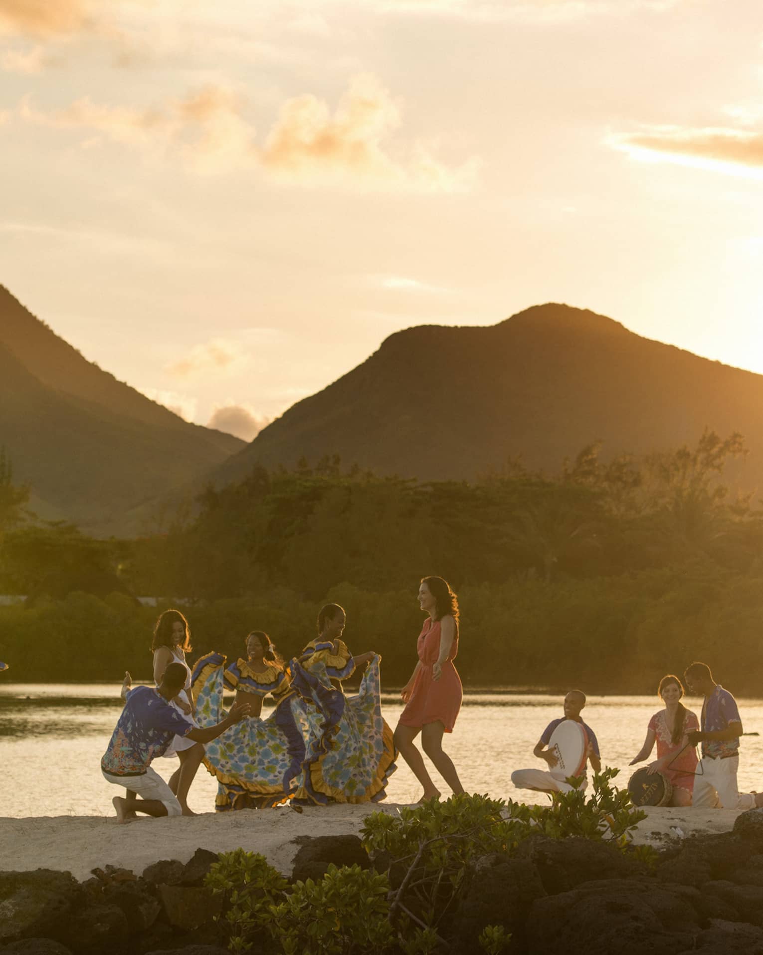 A group of people dancing near water.