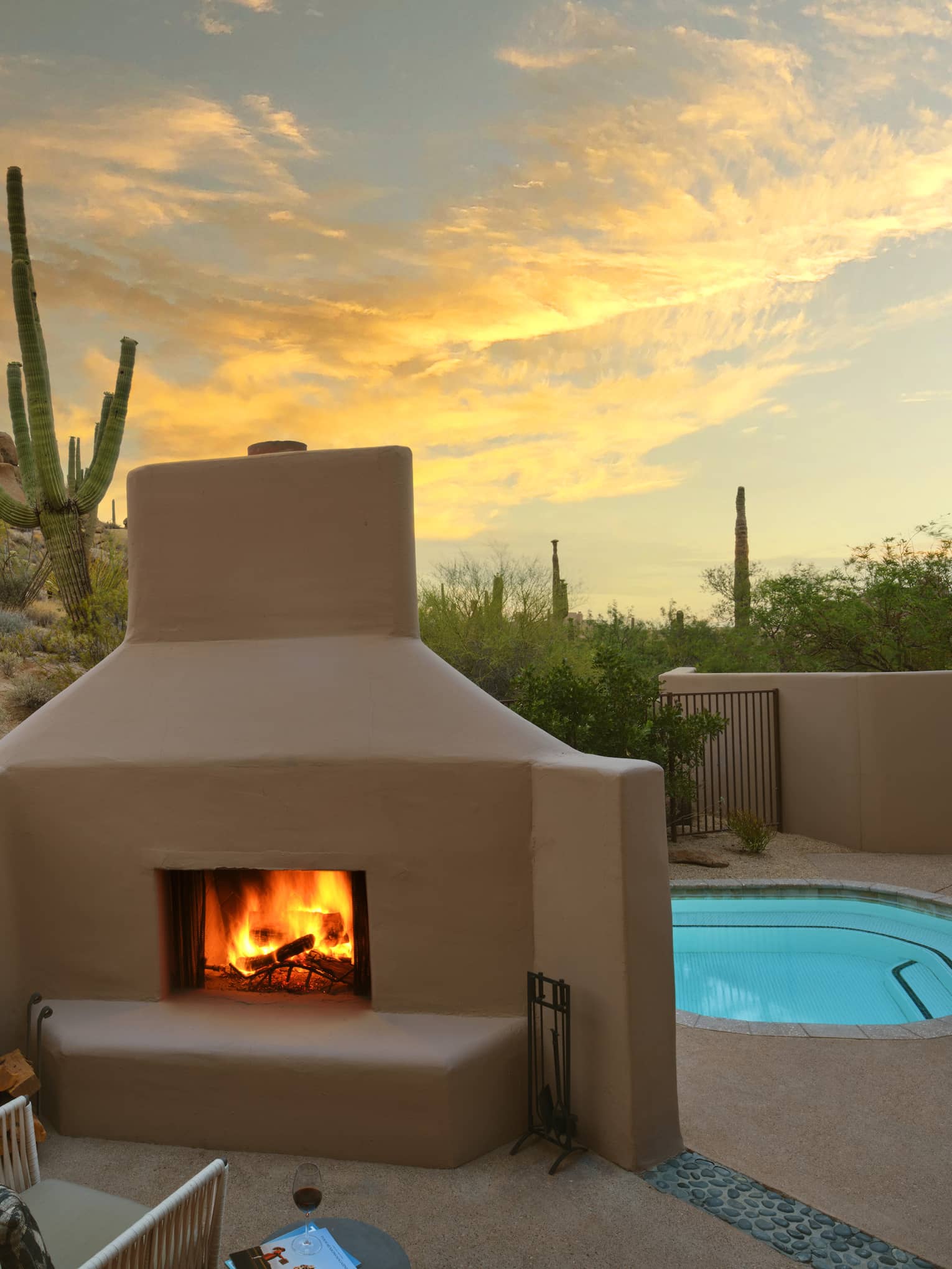 A pool beside a fire pit with a chair, surrounded by desert views