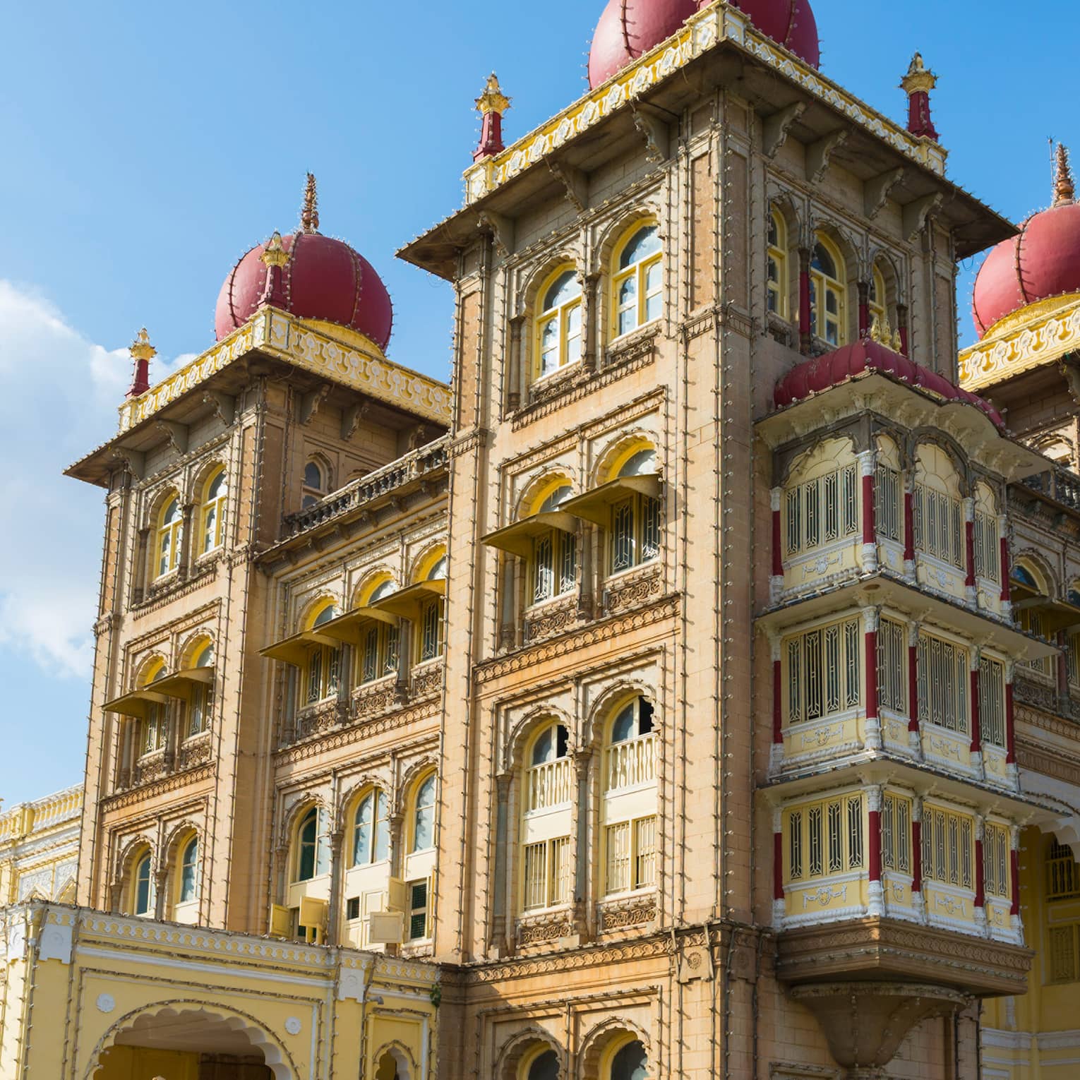 Sprawling palace with arched windows, dome-topped towers and an ornate design, its golden hue contrasted against a sunny sky.