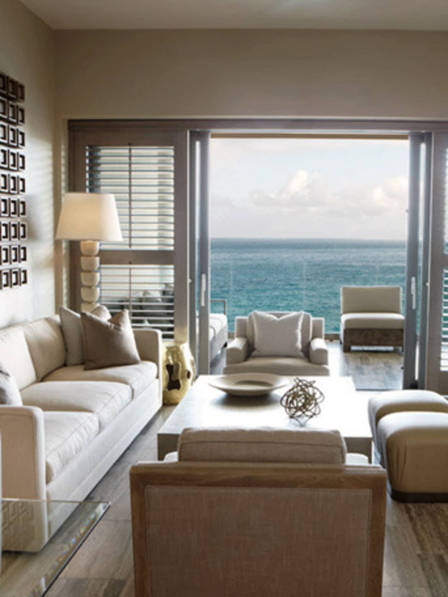 Modern living room with neutral décor, large glass doors and ocean view balcony