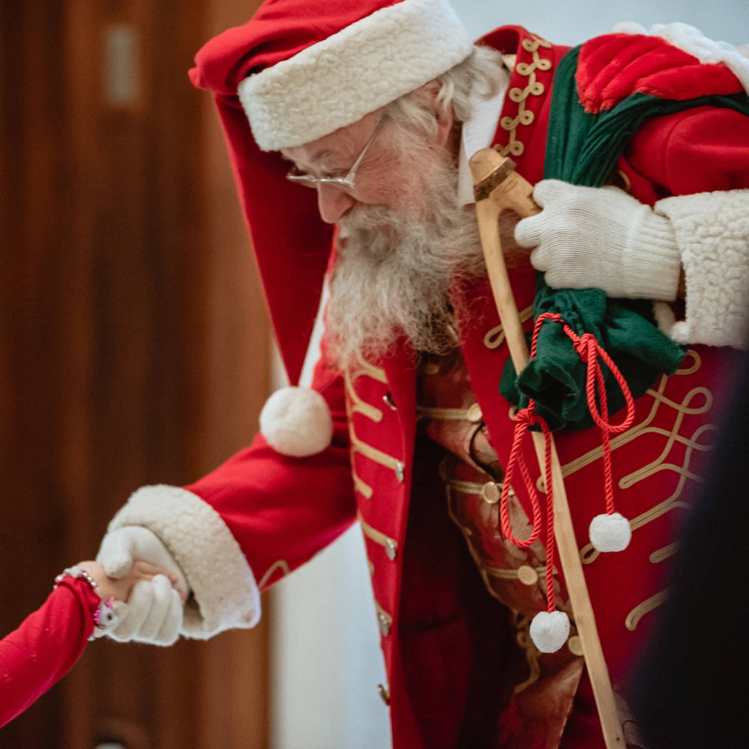 A man dressed as Santa Claus shakes little girl's hand