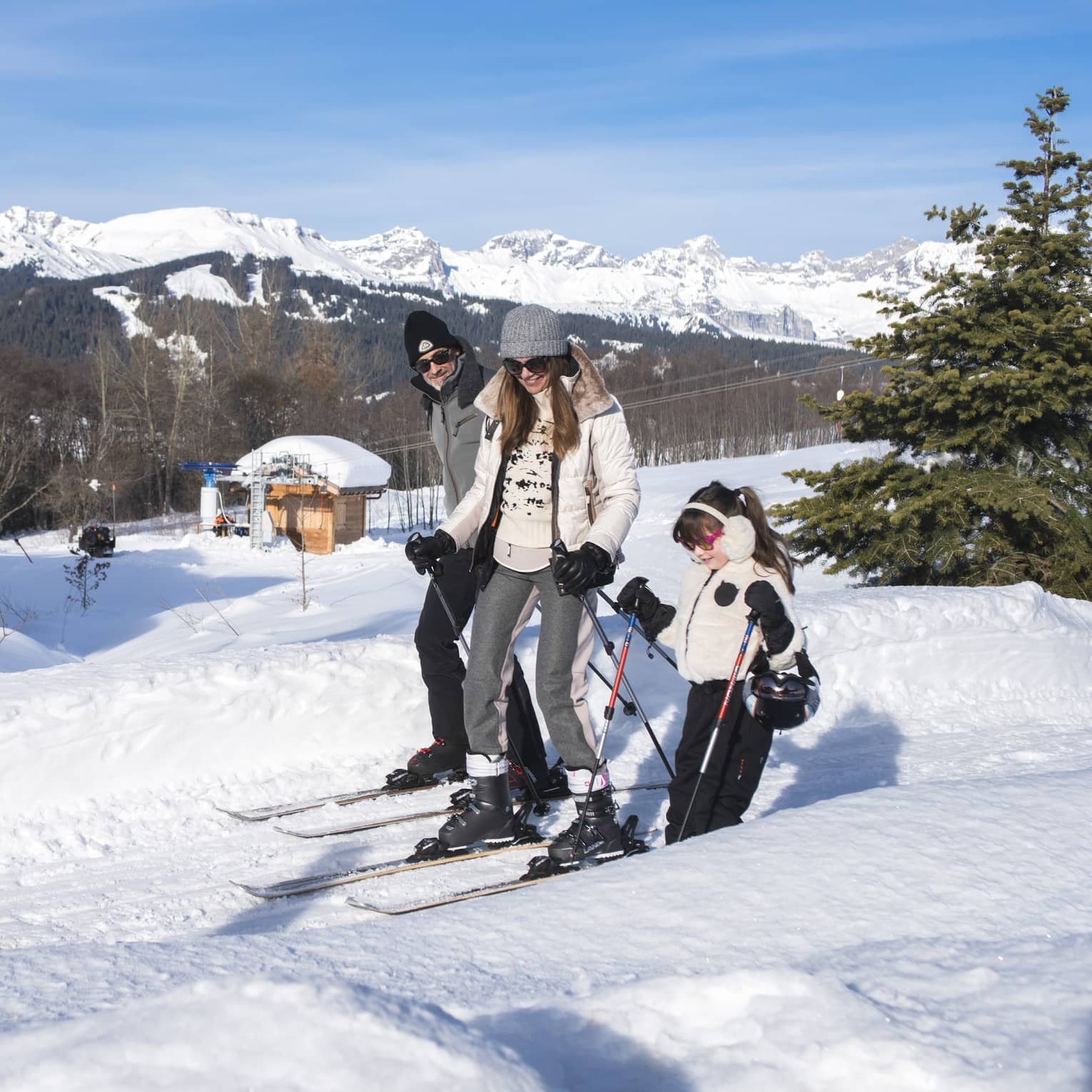 A father, mother and daughter on skis standing on snow.