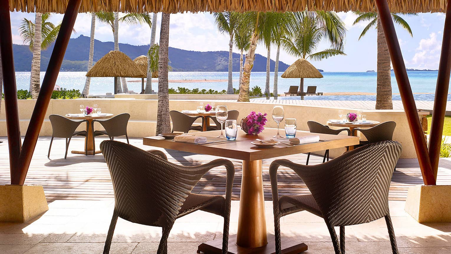 Tere Nui dining table with wicker chair looking out at sunny patio, ocean