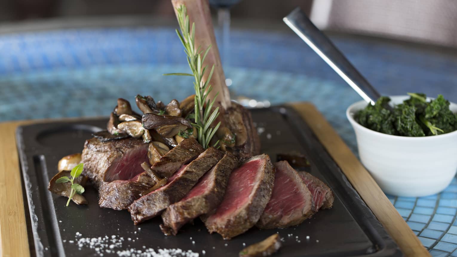 Several slices of sirloin served on a black platter with roasted broccoli.