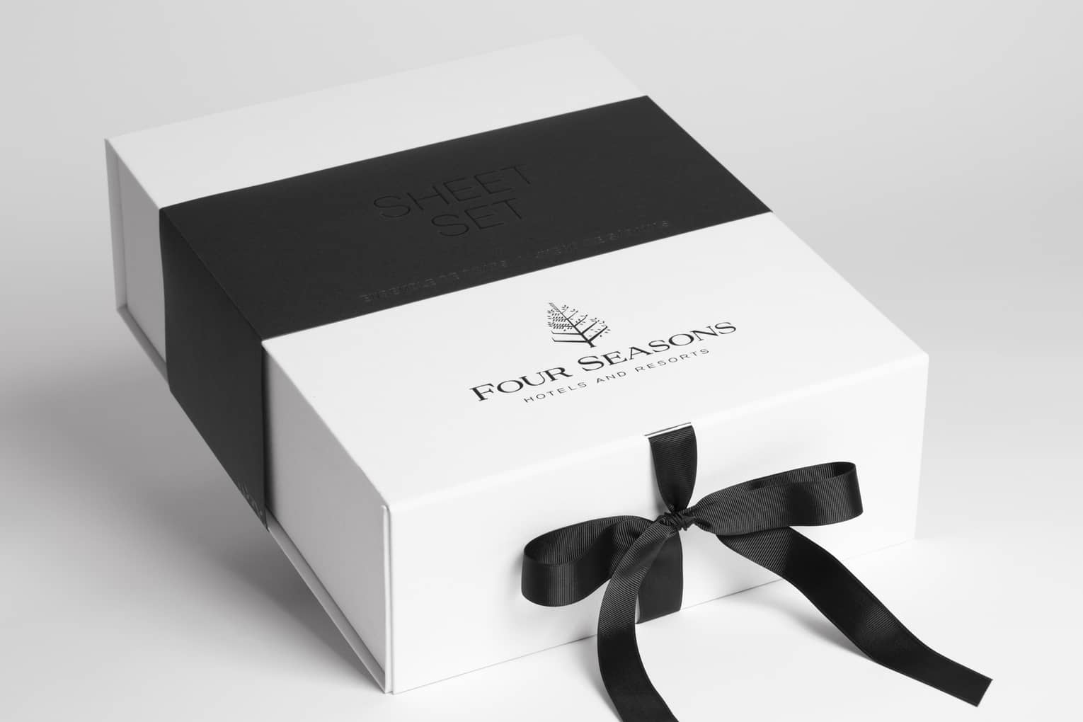 A white four seasons gift card packaging with a black ribbon tied around it