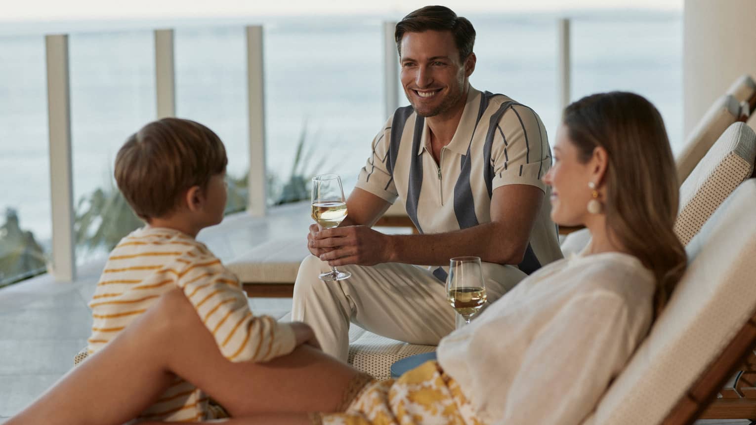 Family lounging in outdoor chairs with glasses of wine.