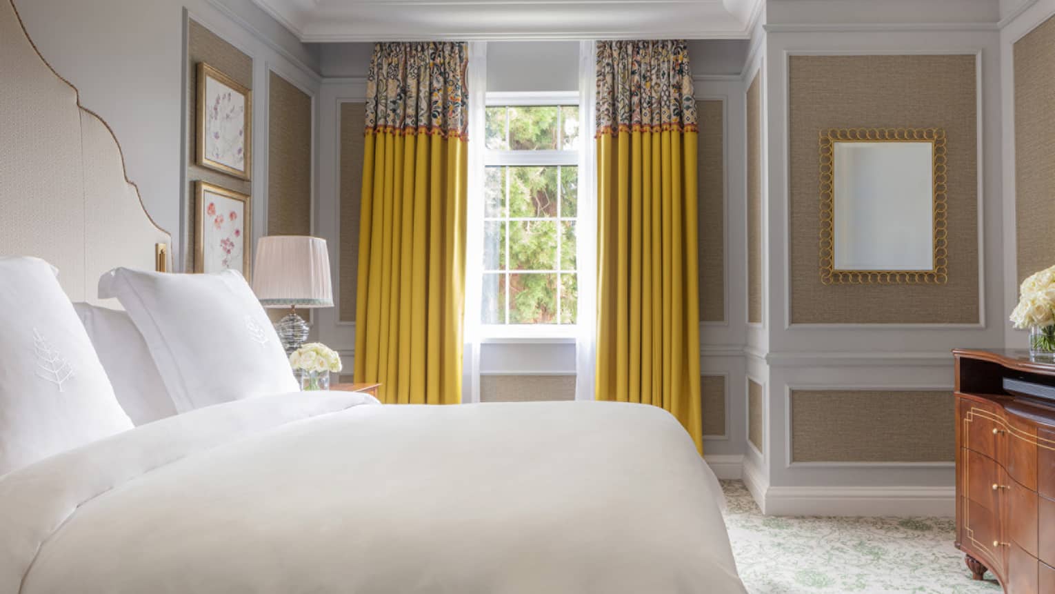 Guest room with Queen bed, white linens, paisley carpeting, cherry wardrobe, window with yellow drapes