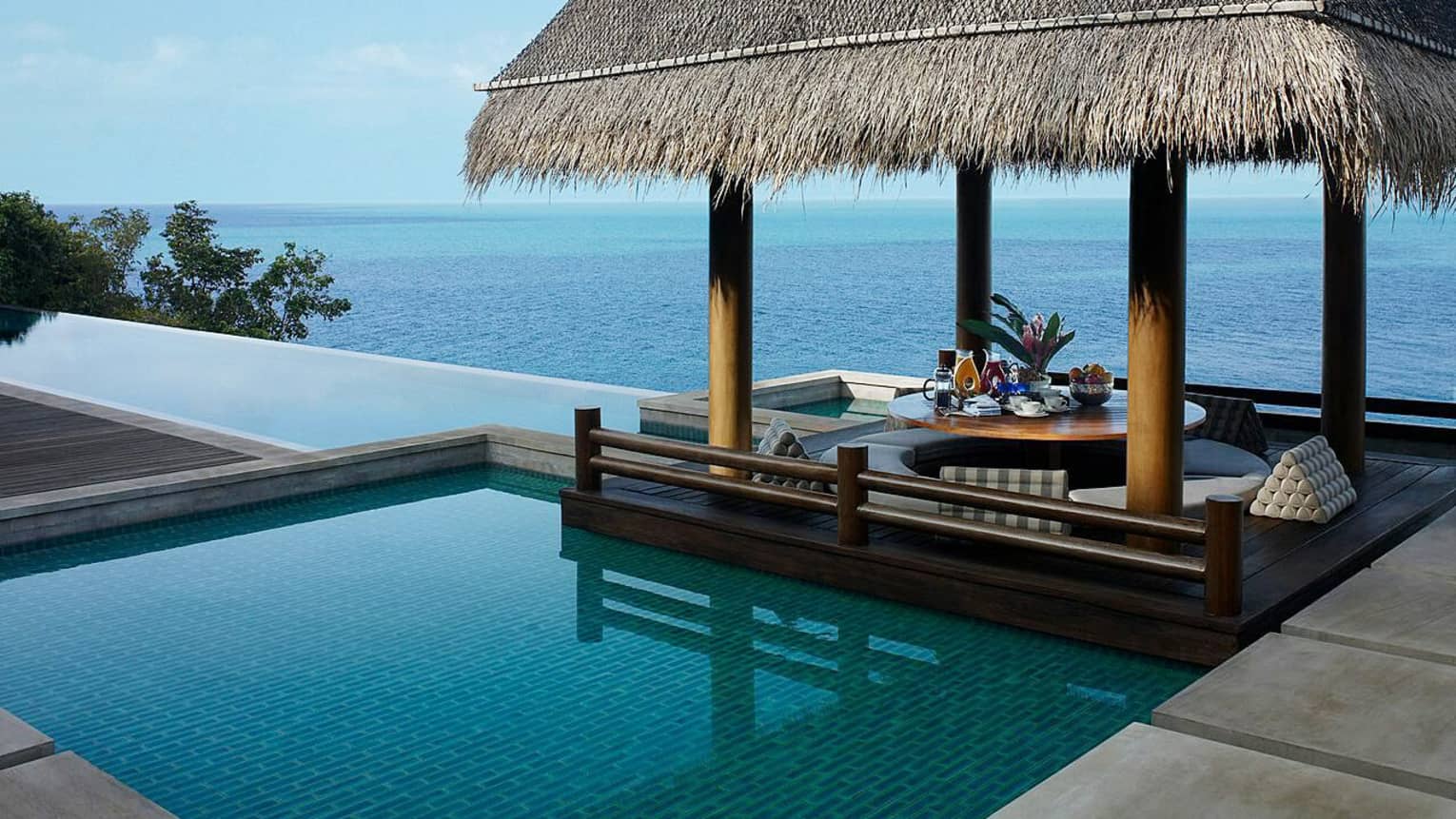 Patio cabana with thatched-roof by small plunge swimming pool overlooking ocean