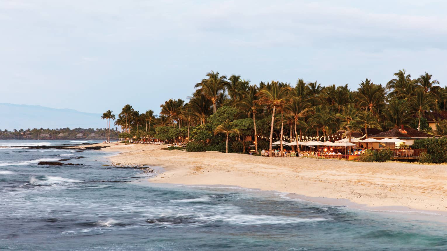  View over ocean and white sand beach to event on resort lawn