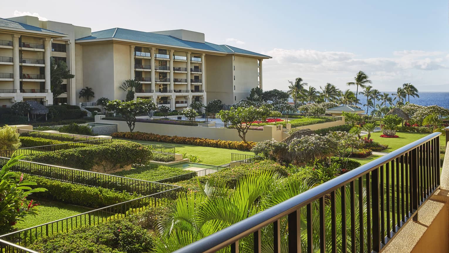 Four Seasons luxury resort grounds with well-kept gardens, pool, palm trees and ocean view, featuring a large multi-story building