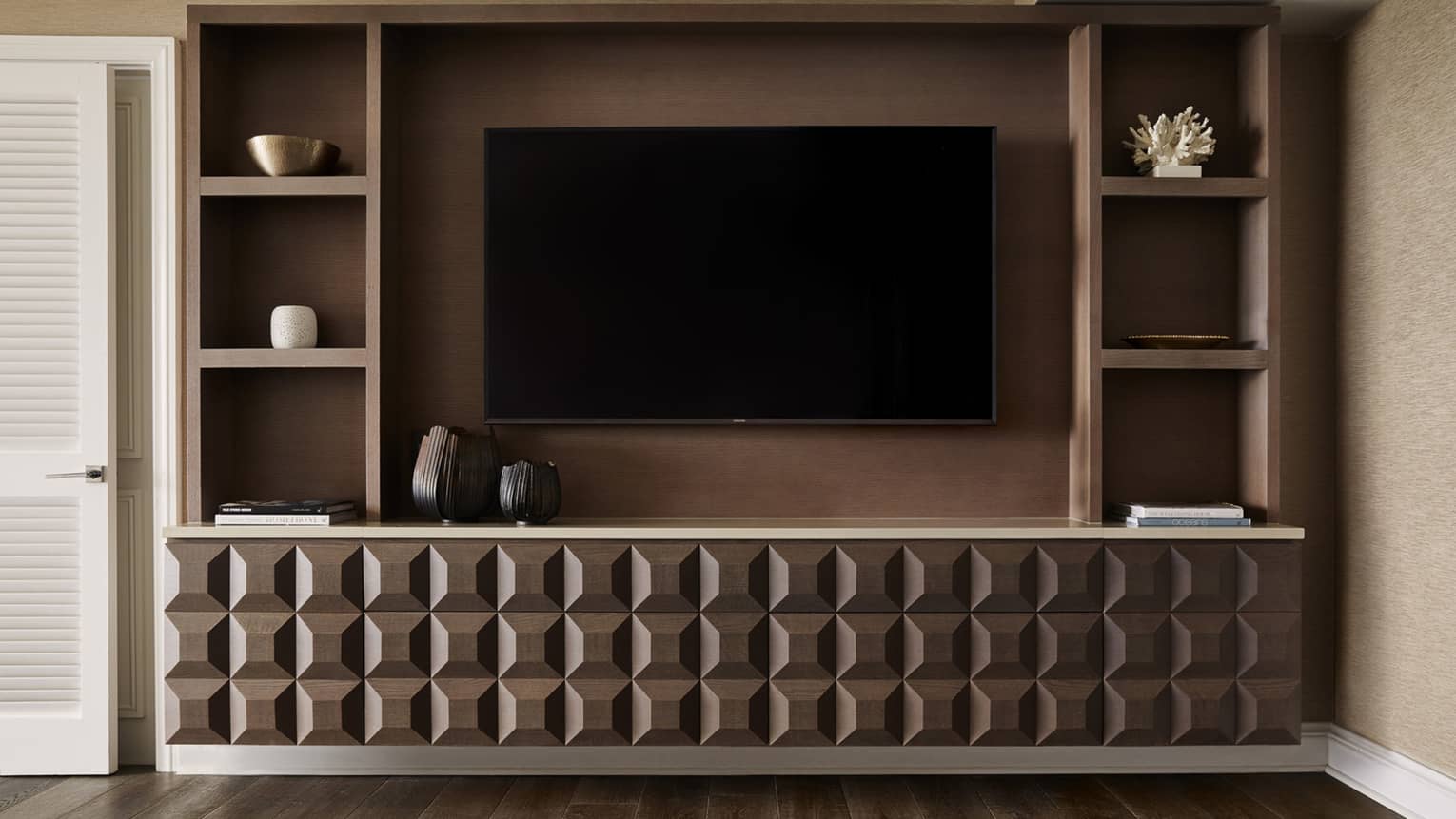 Modern entertainment center with geometric wood design, mounted TV and shelving