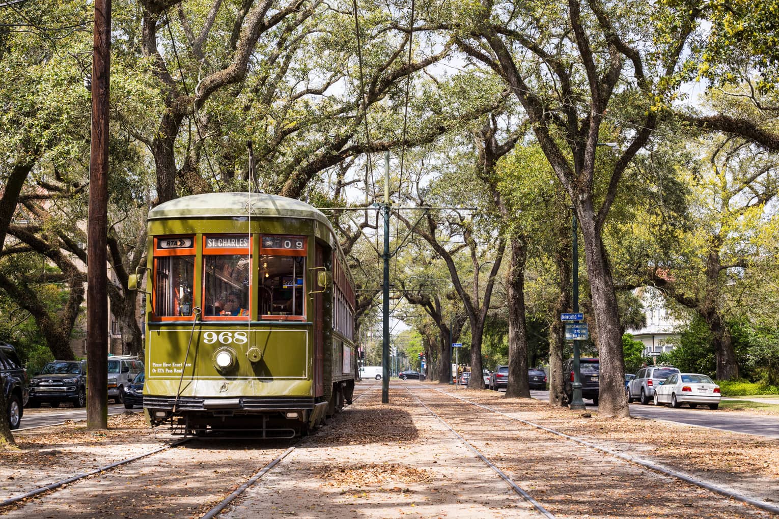 Vintage streetcar on track between trees on New Orleans street