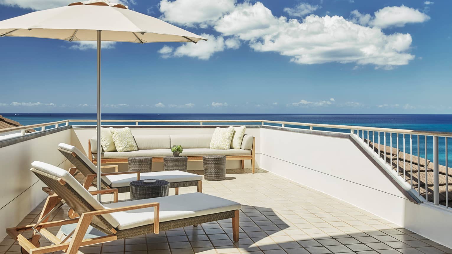 White cushioned wicker patio furniture, umbrella on rooftop balcony